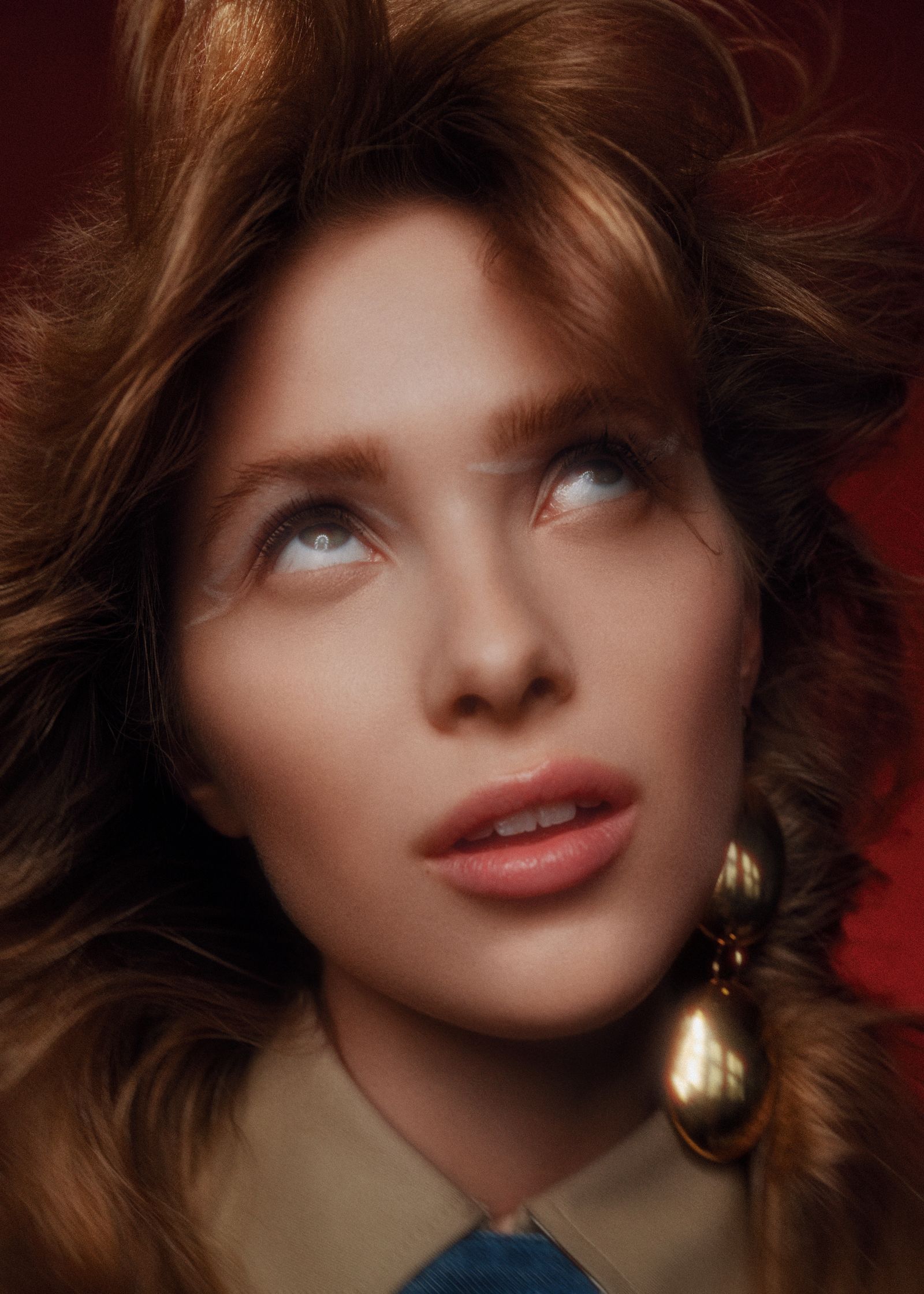 a woman with long hair and earrings looking up at the camera
