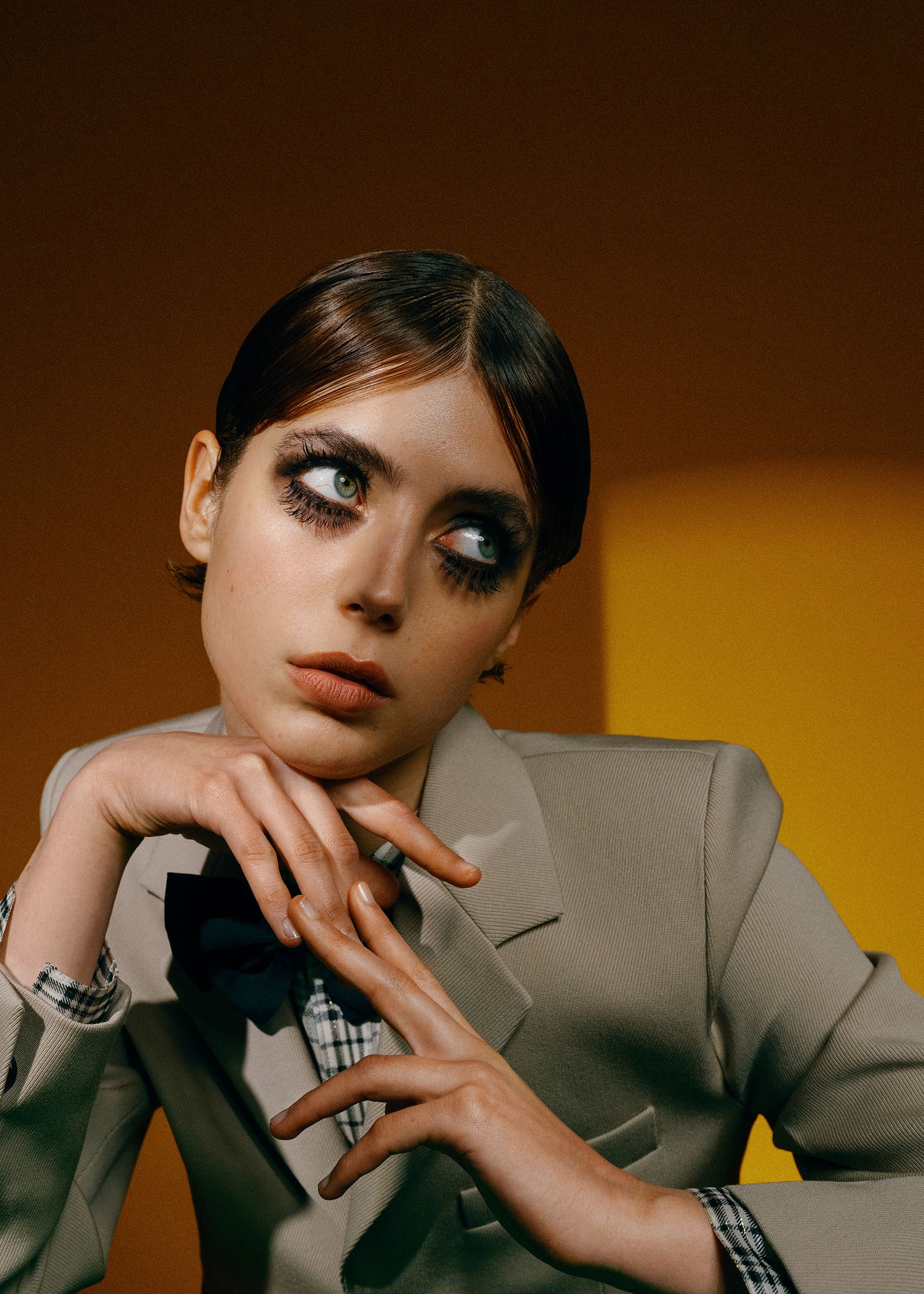a woman in a suit with her hand on her chin