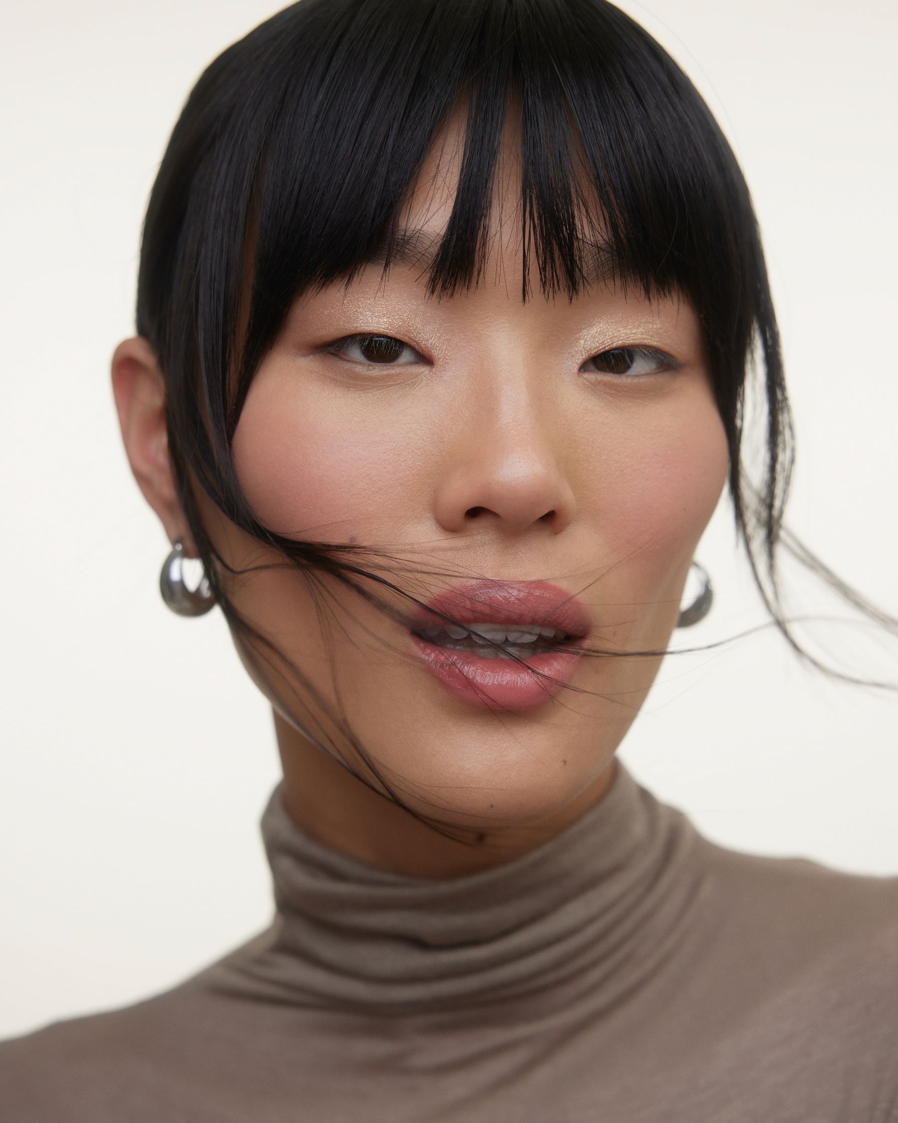 an asian woman wearing a turtle neck with bangs