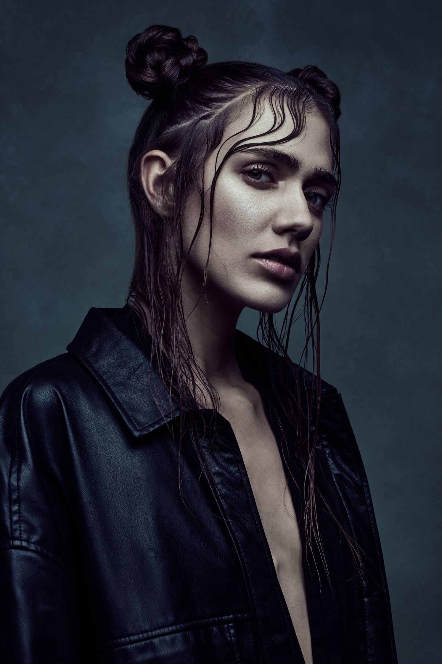 Portrait of model Ilona Gachet wearing a black leather coat with a Matrix-inspired look, featuring wet hair styled in an edgy updo.