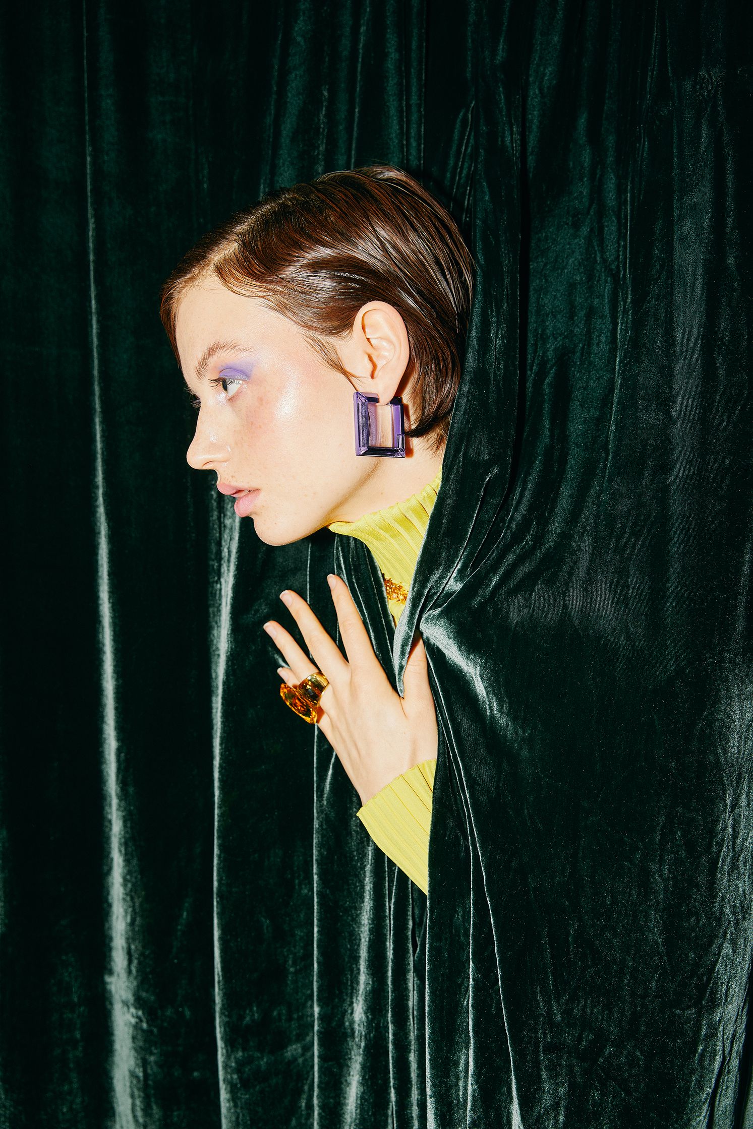 a woman is hiding behind a green velvet curtain