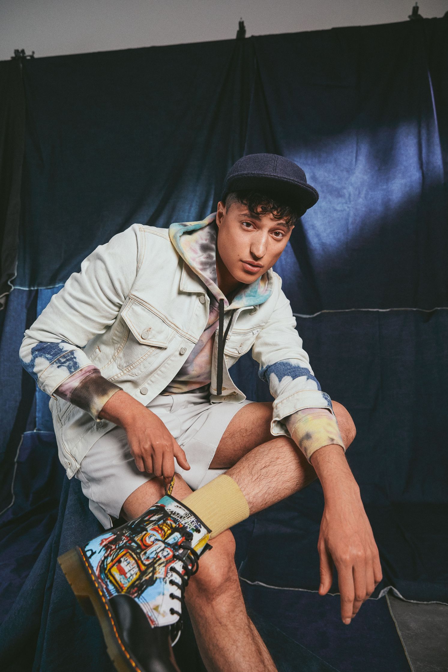 a man sitting on a blue blanket with a pair of dr martens sneakers