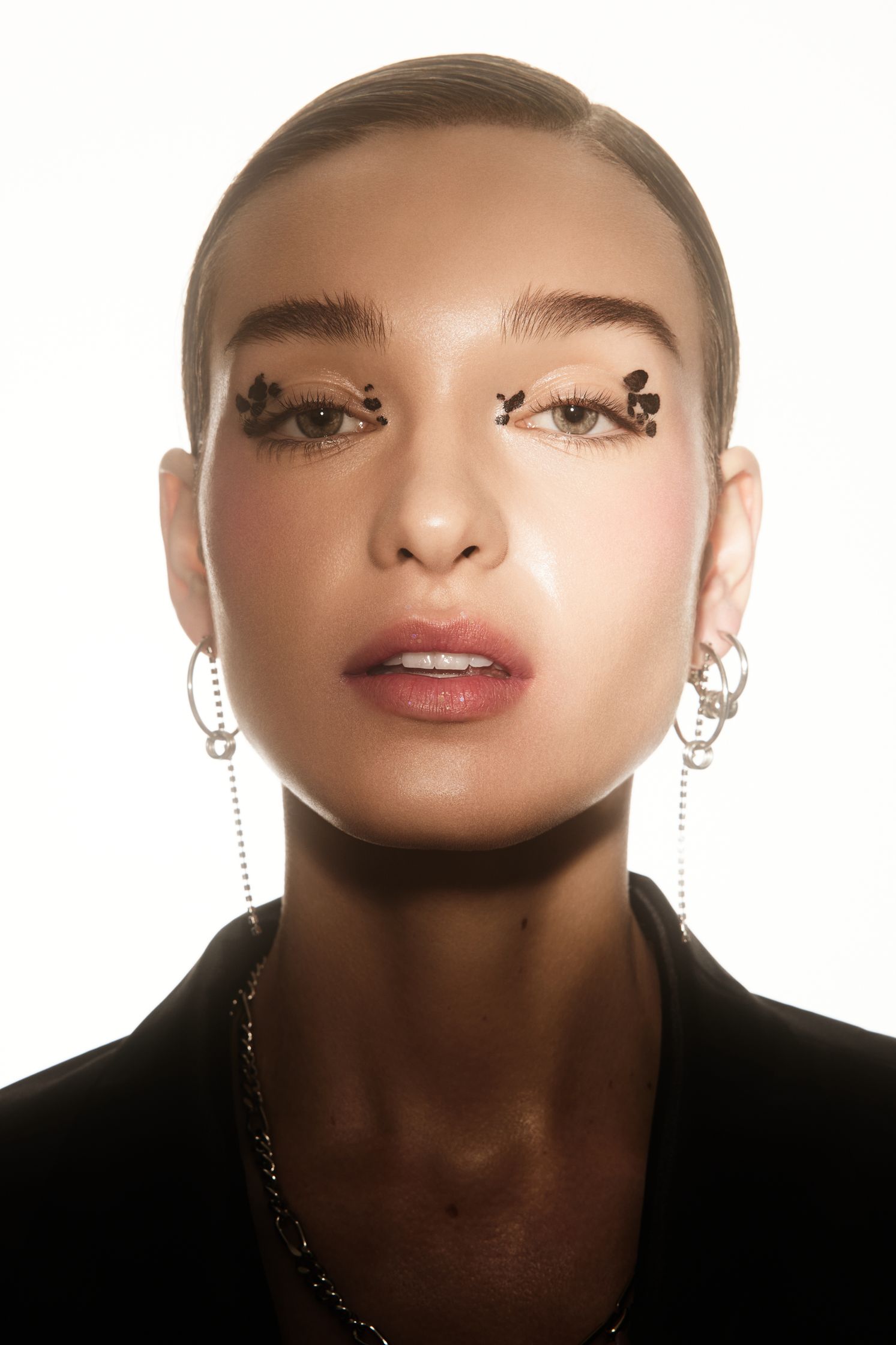 a woman wearing a black jacket and a pair of earrings