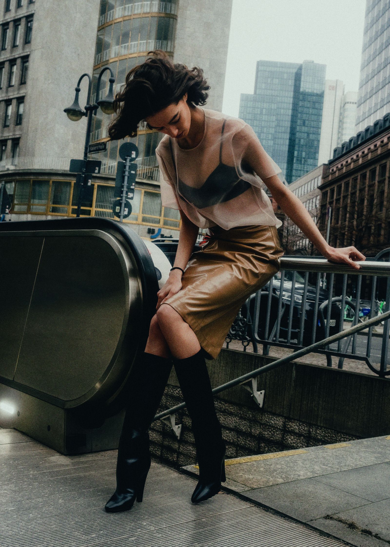 a woman is leaning on an escalator in a city