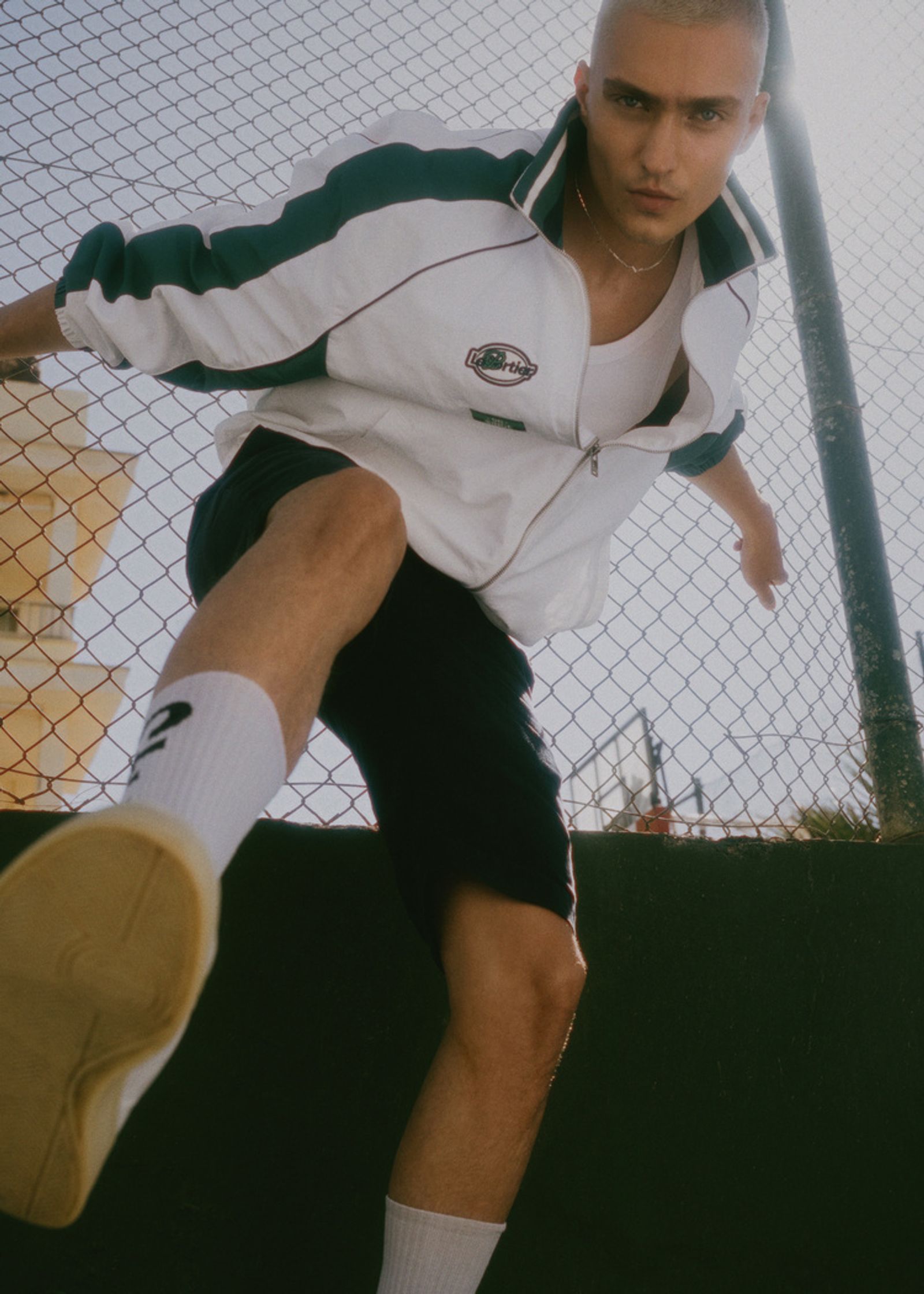 a man wearing a white and green track jacket and sneakers