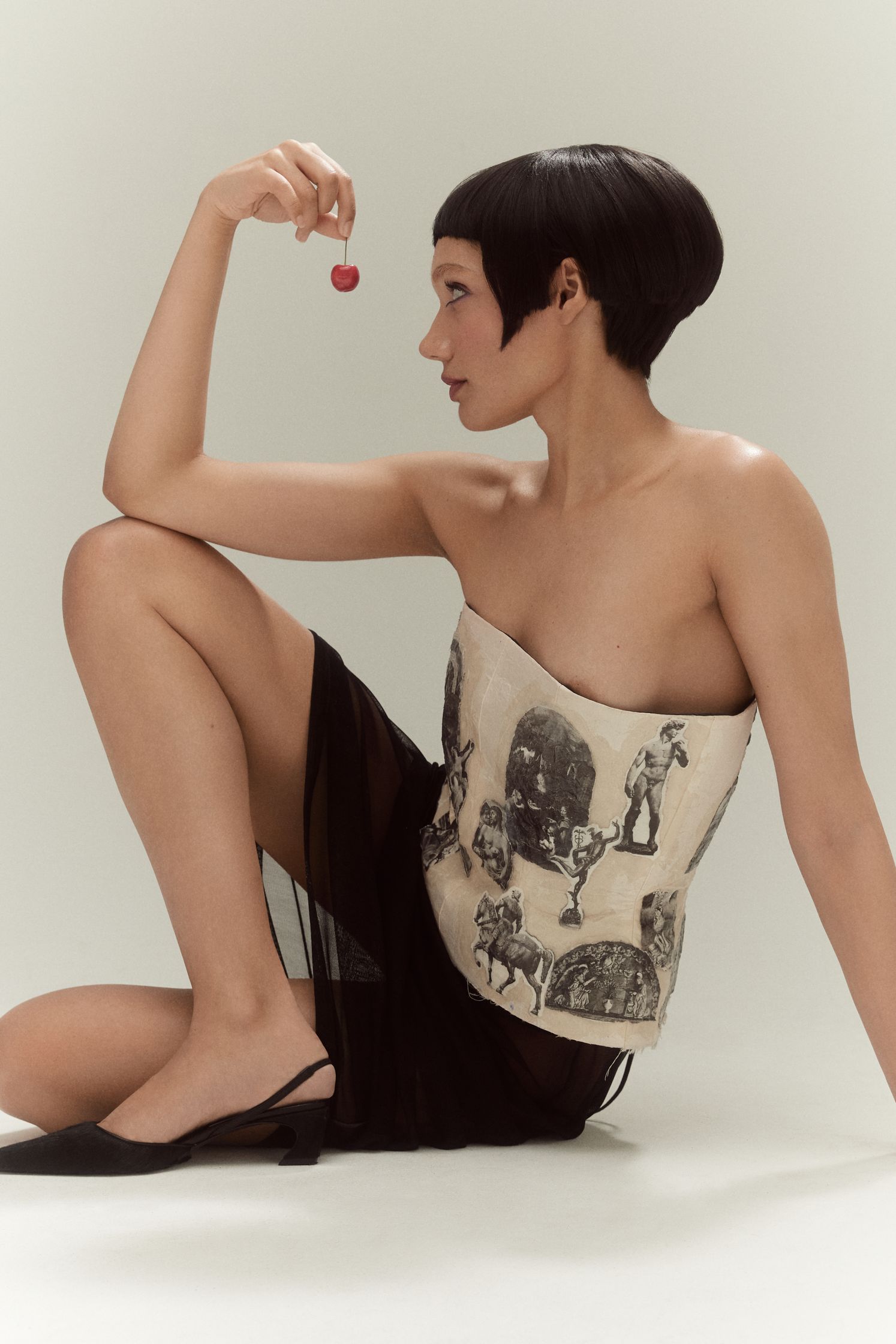 a woman sitting on the floor holding a strawberry