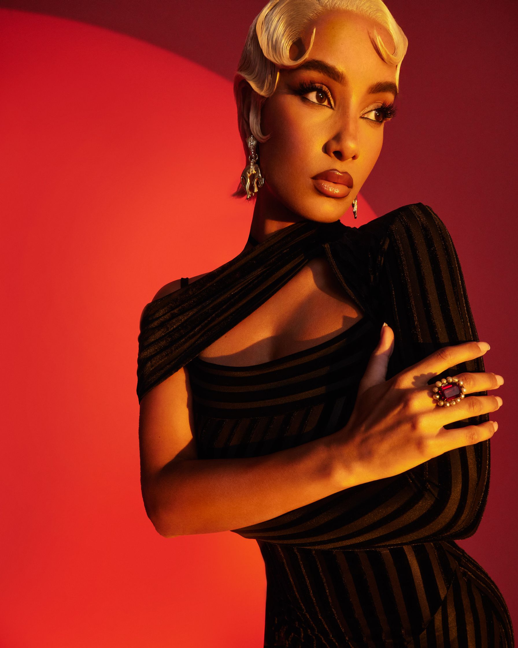 a woman in a black dress posing against a red background