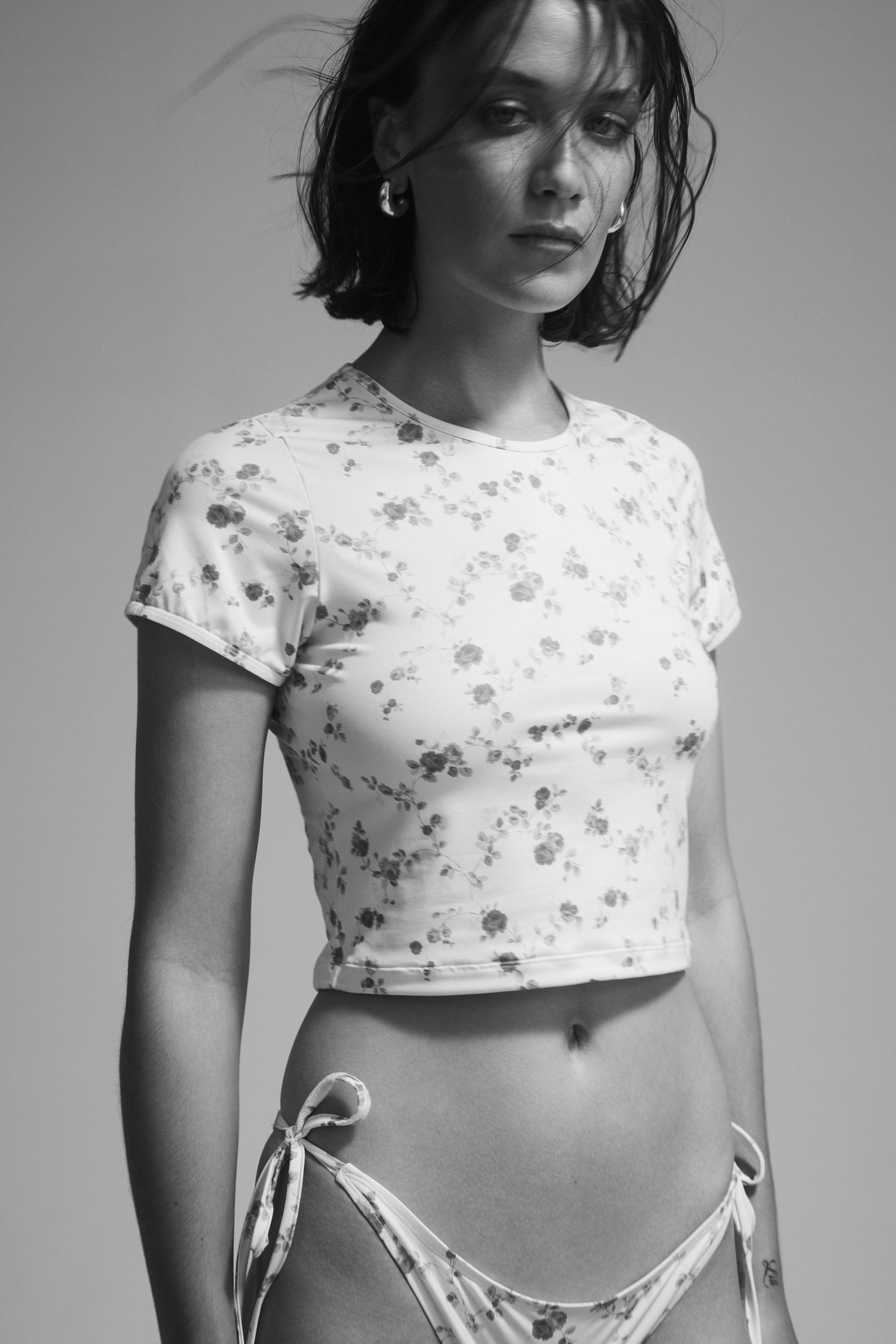 a woman in a floral bikini posing in a black and white photo
