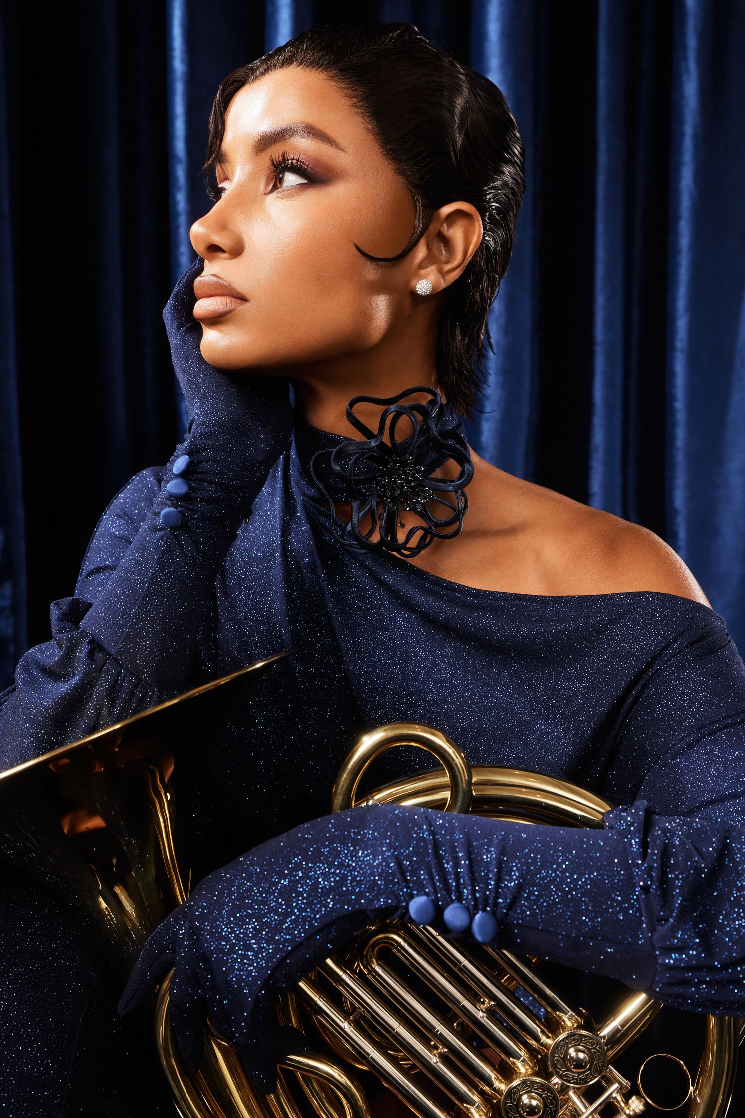 a woman in a blue dress holding a brass instrument