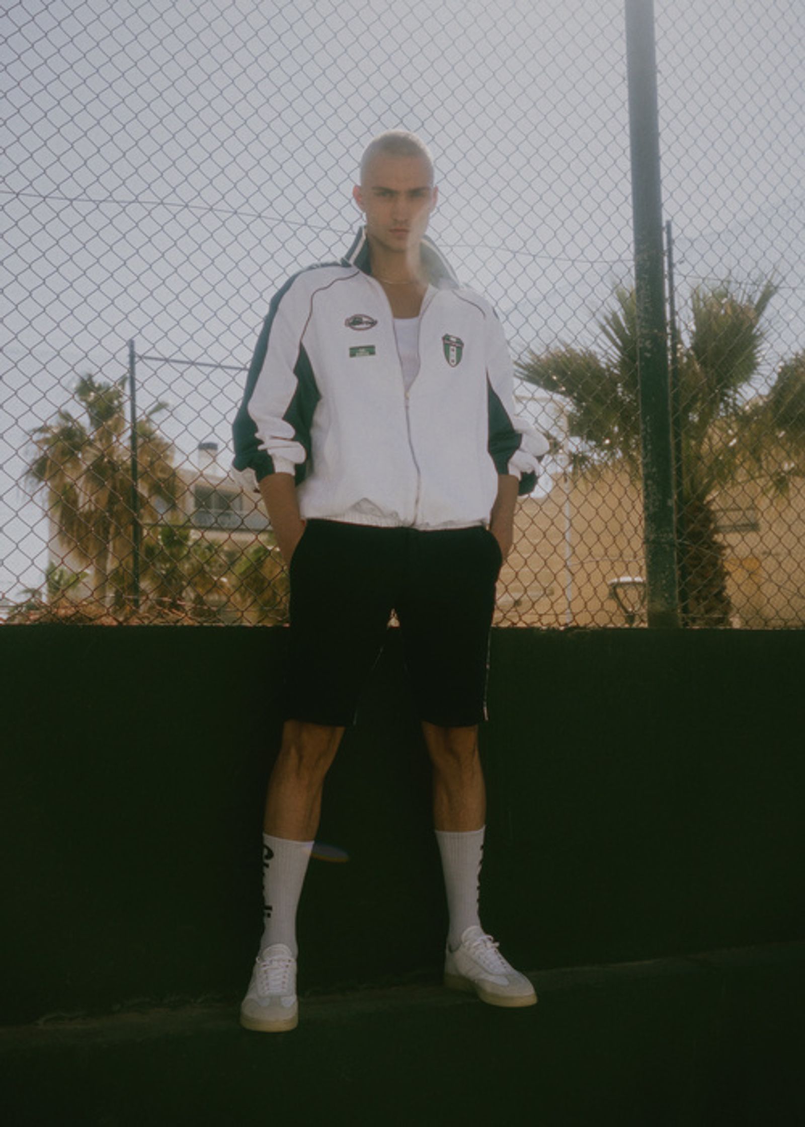 a man is posing for a photo in front of a fence