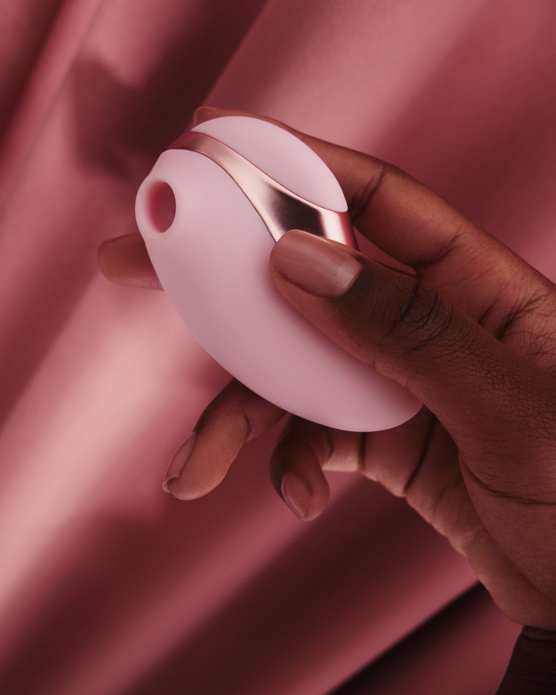 a woman's hand holding a pink vibrator