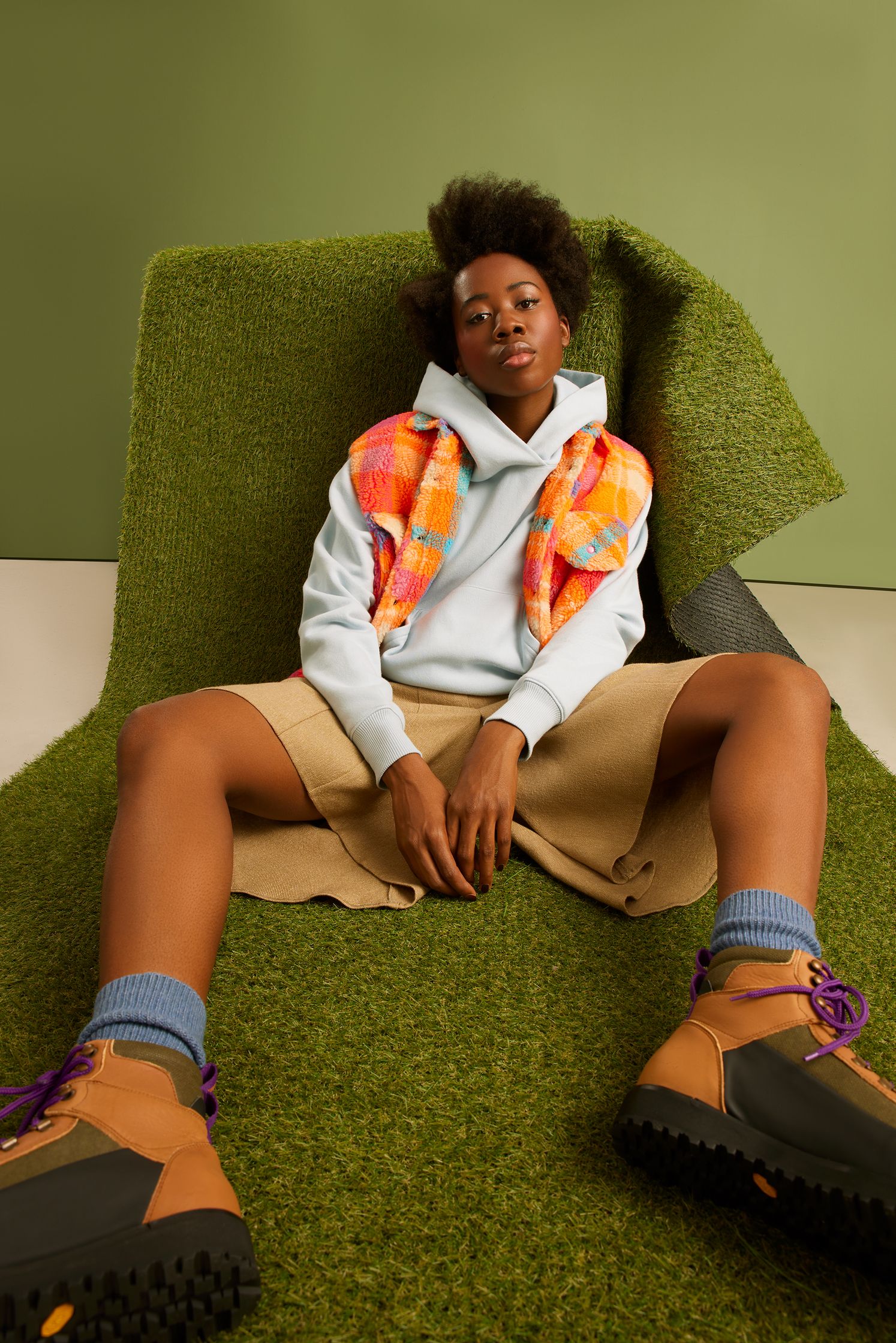 a woman in a hoodie and shorts laying on a green carpet
