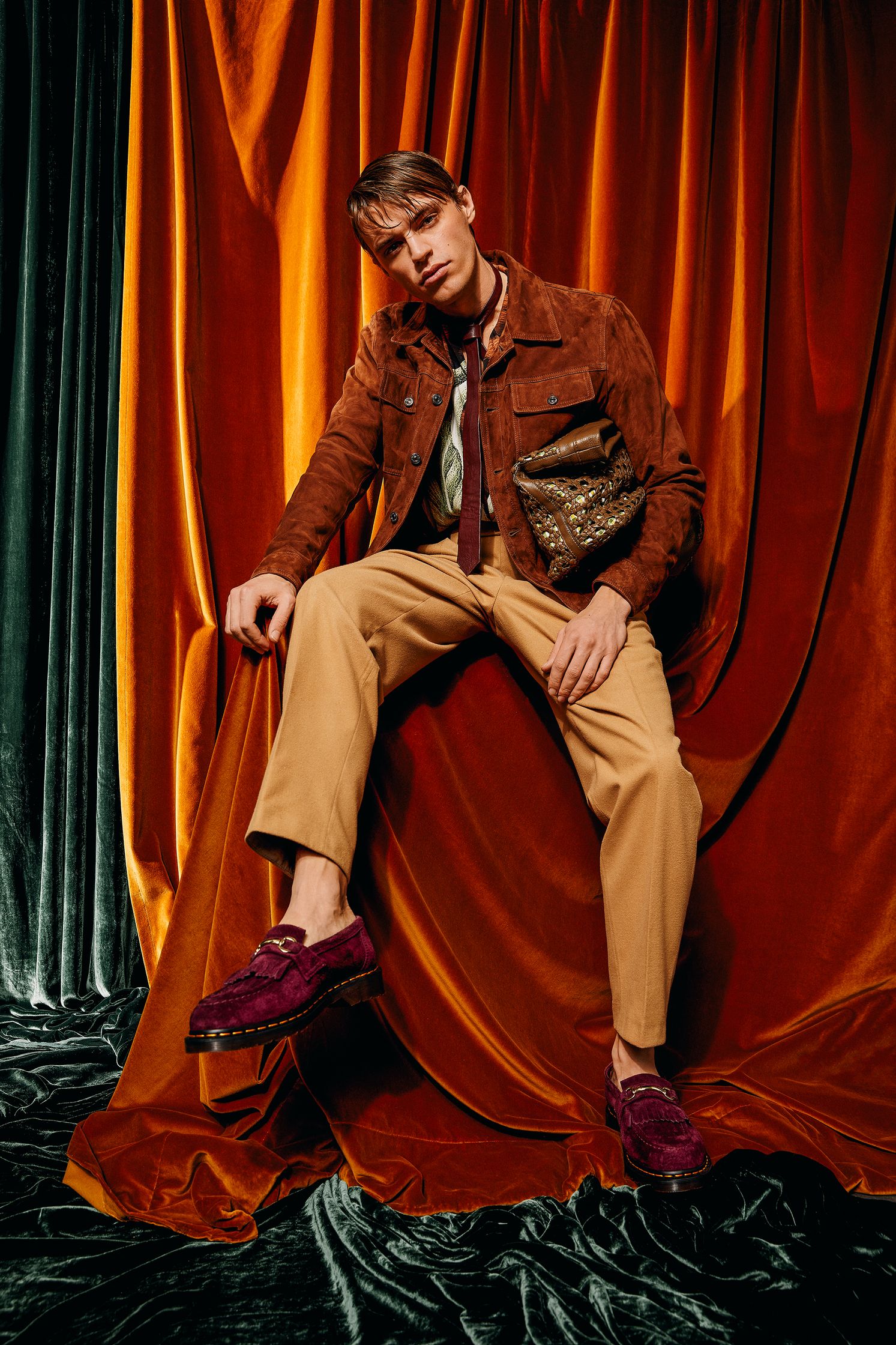 a man in a brown jacket sitting on top of a curtain