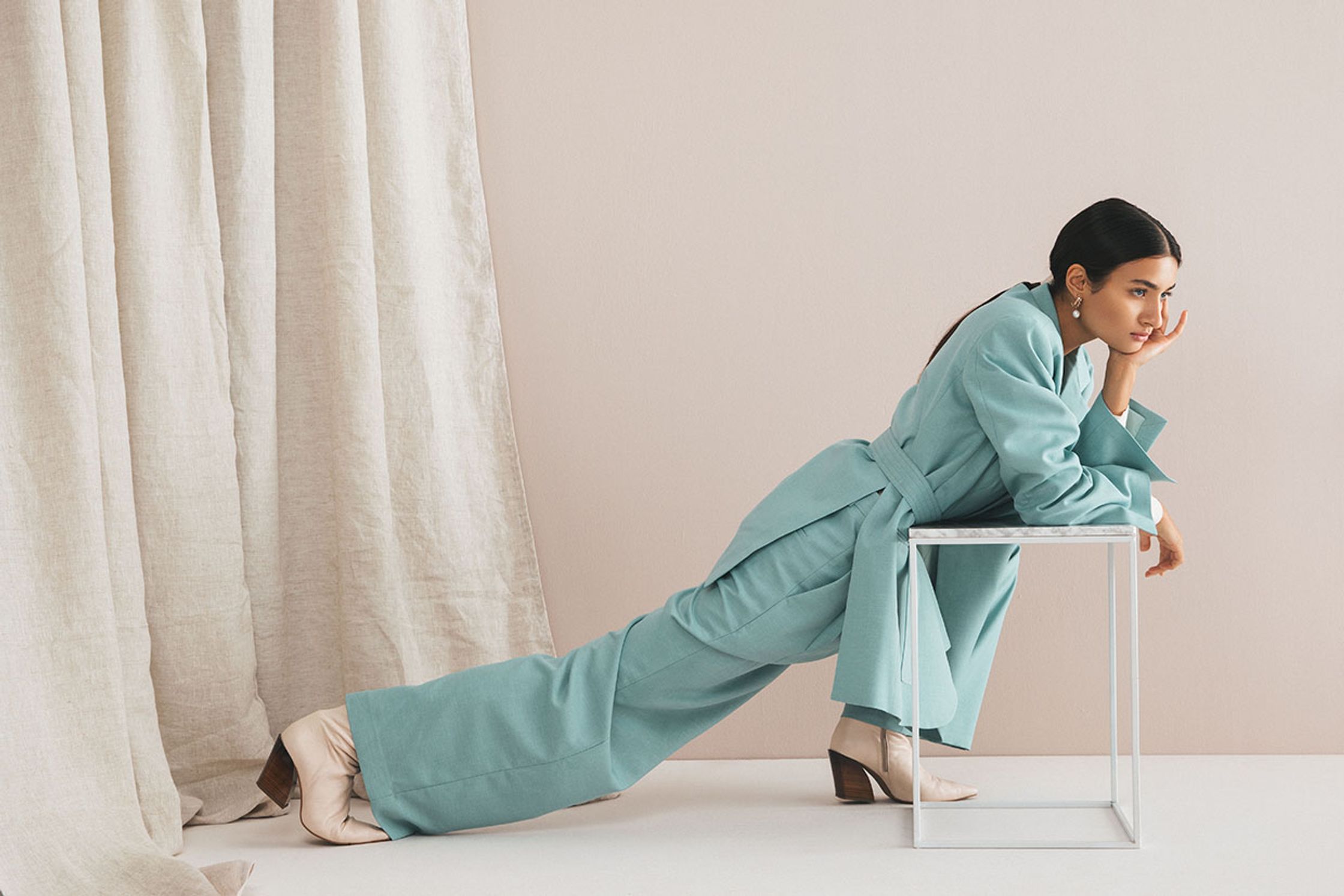 a woman leaning on a chair in a turquoise suit