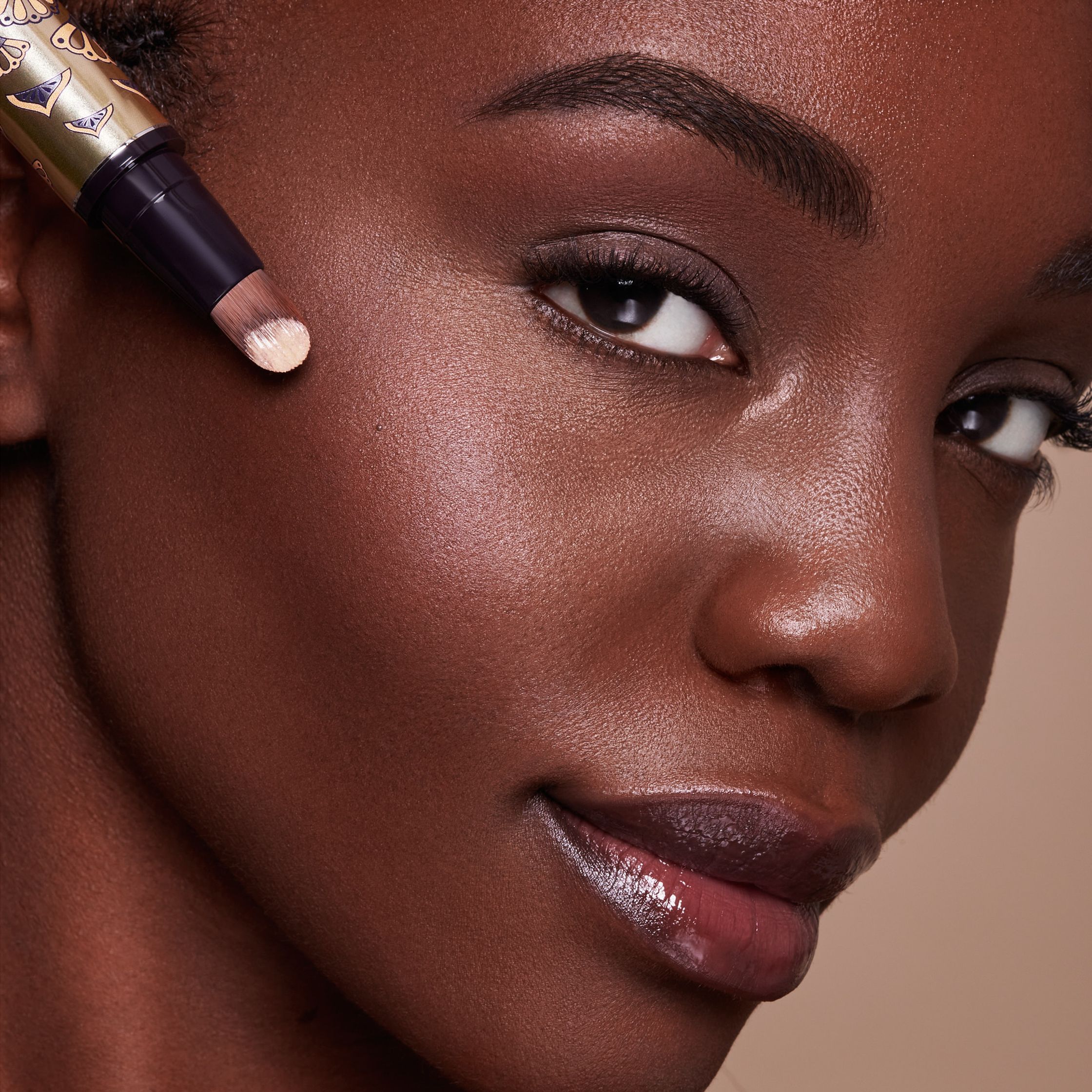 a black woman is holding a makeup brush in her hand