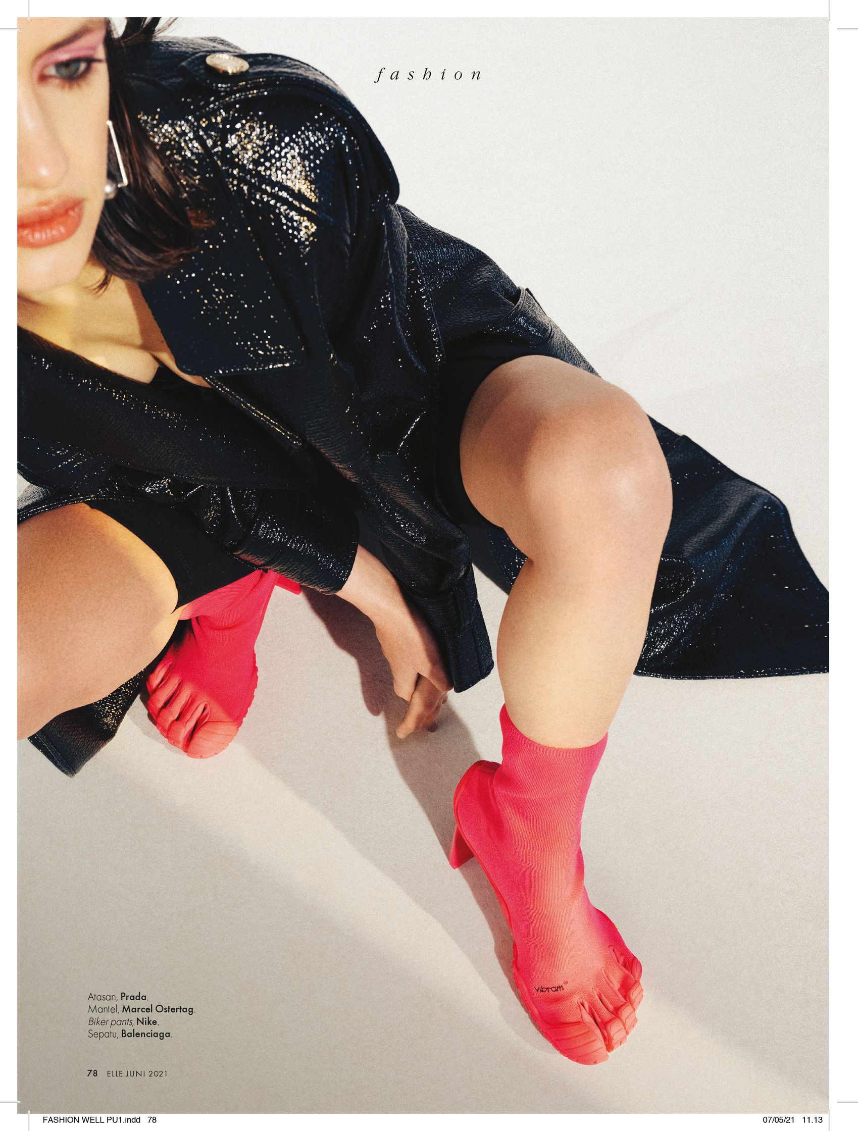 a woman in a black coat and pink heels is posing on the floor