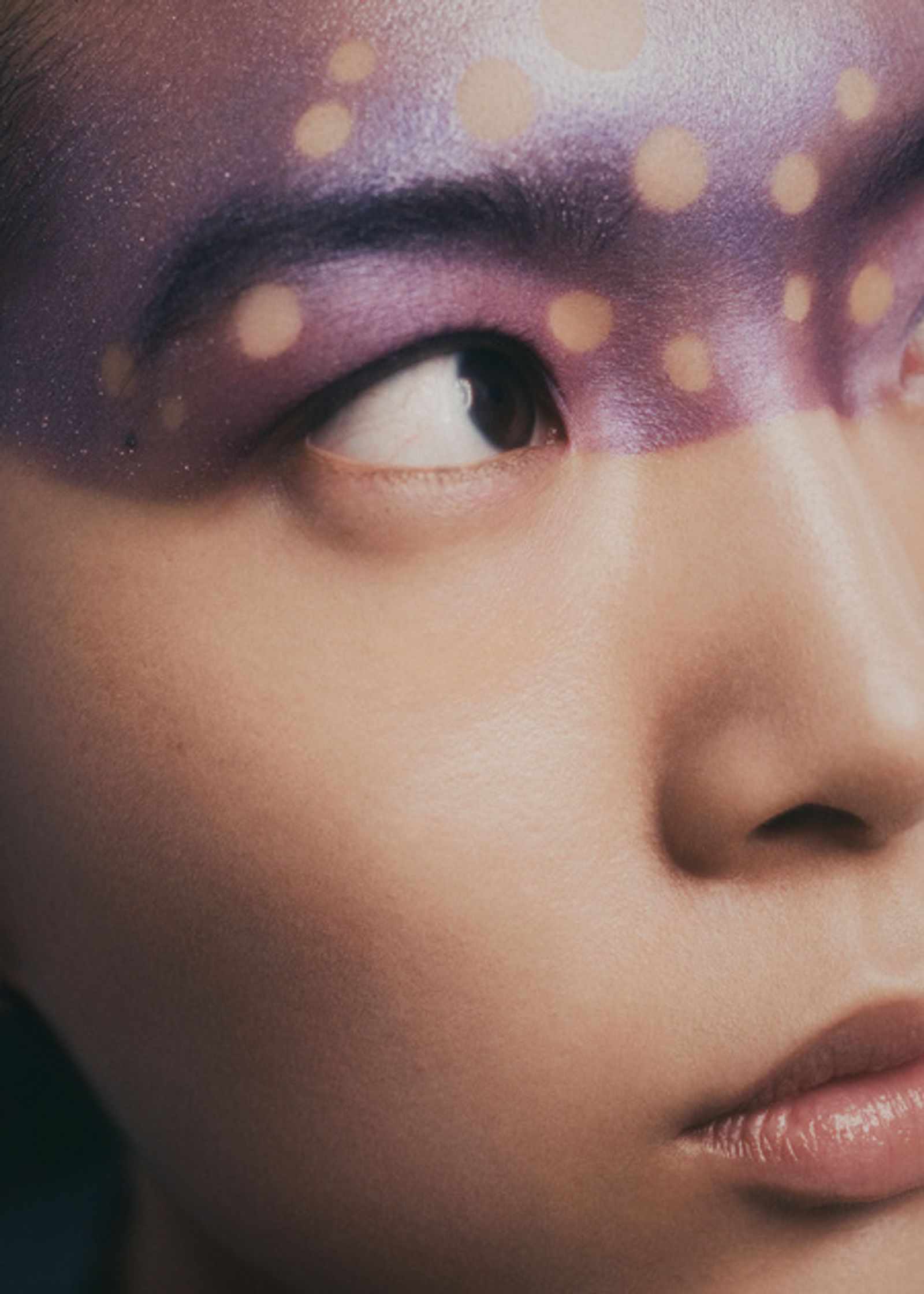 a woman with purple makeup and polka dots on her face