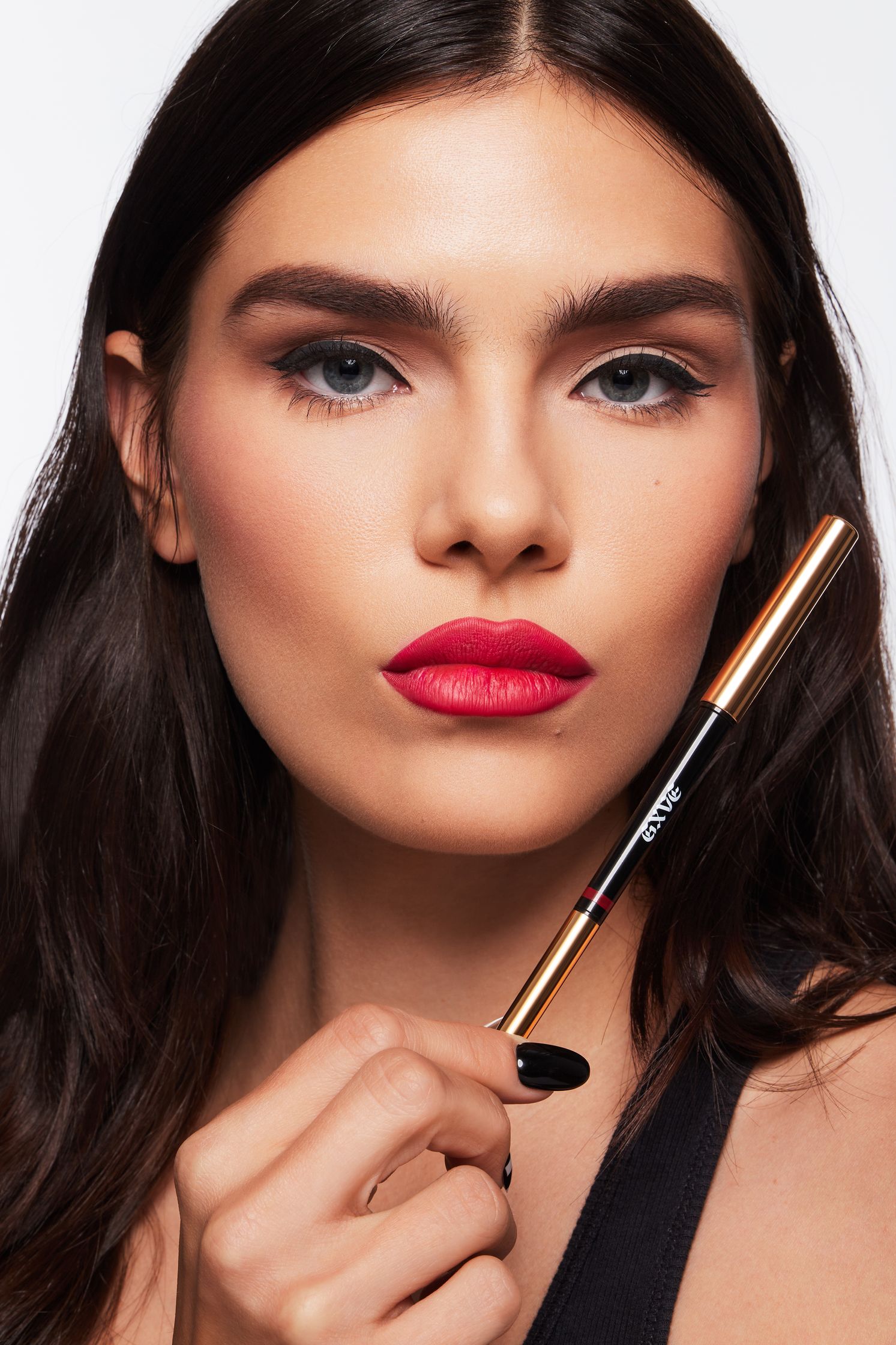a woman is holding a lipstick and a brush