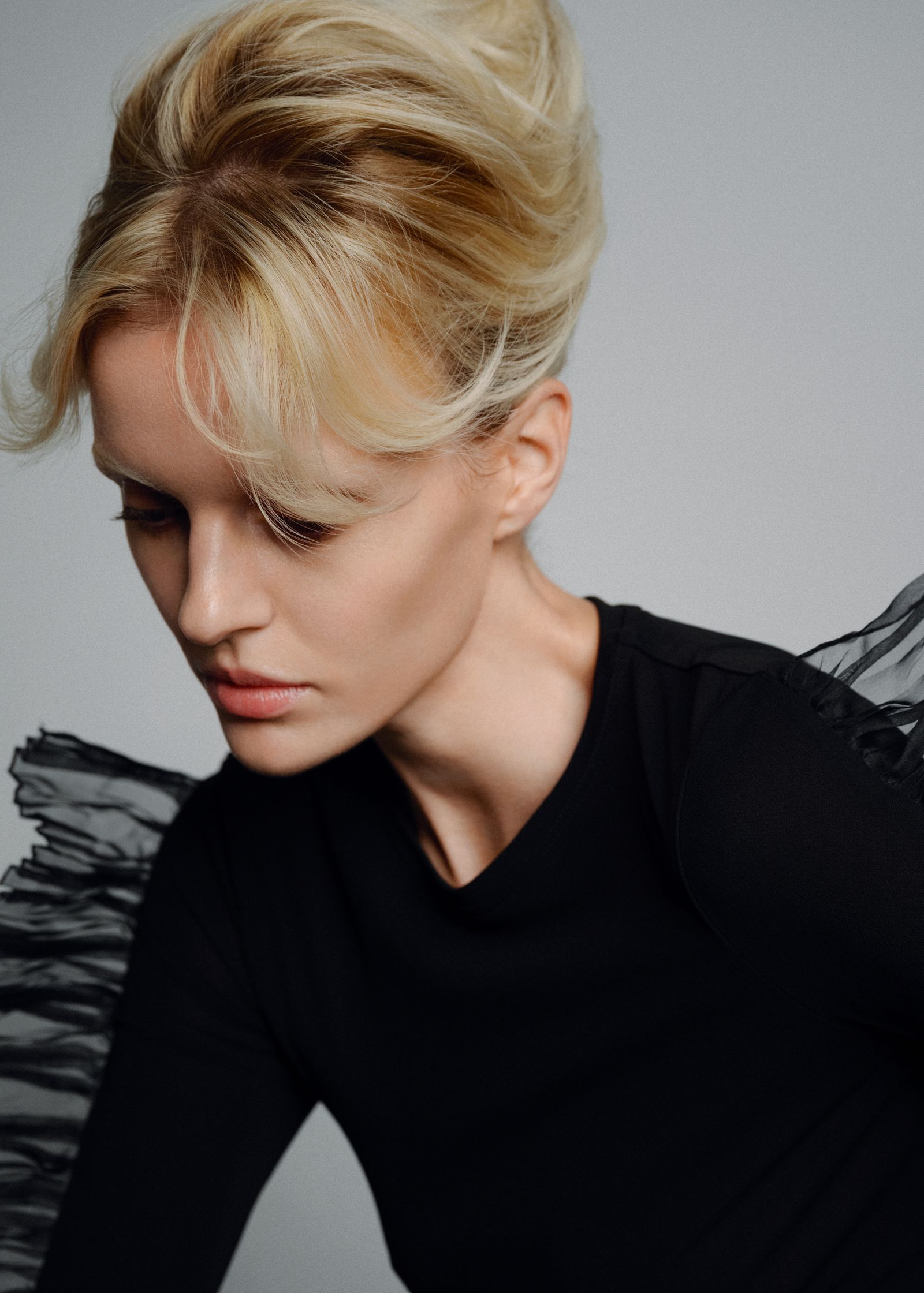 a woman in a black top with a ruffled sleeve