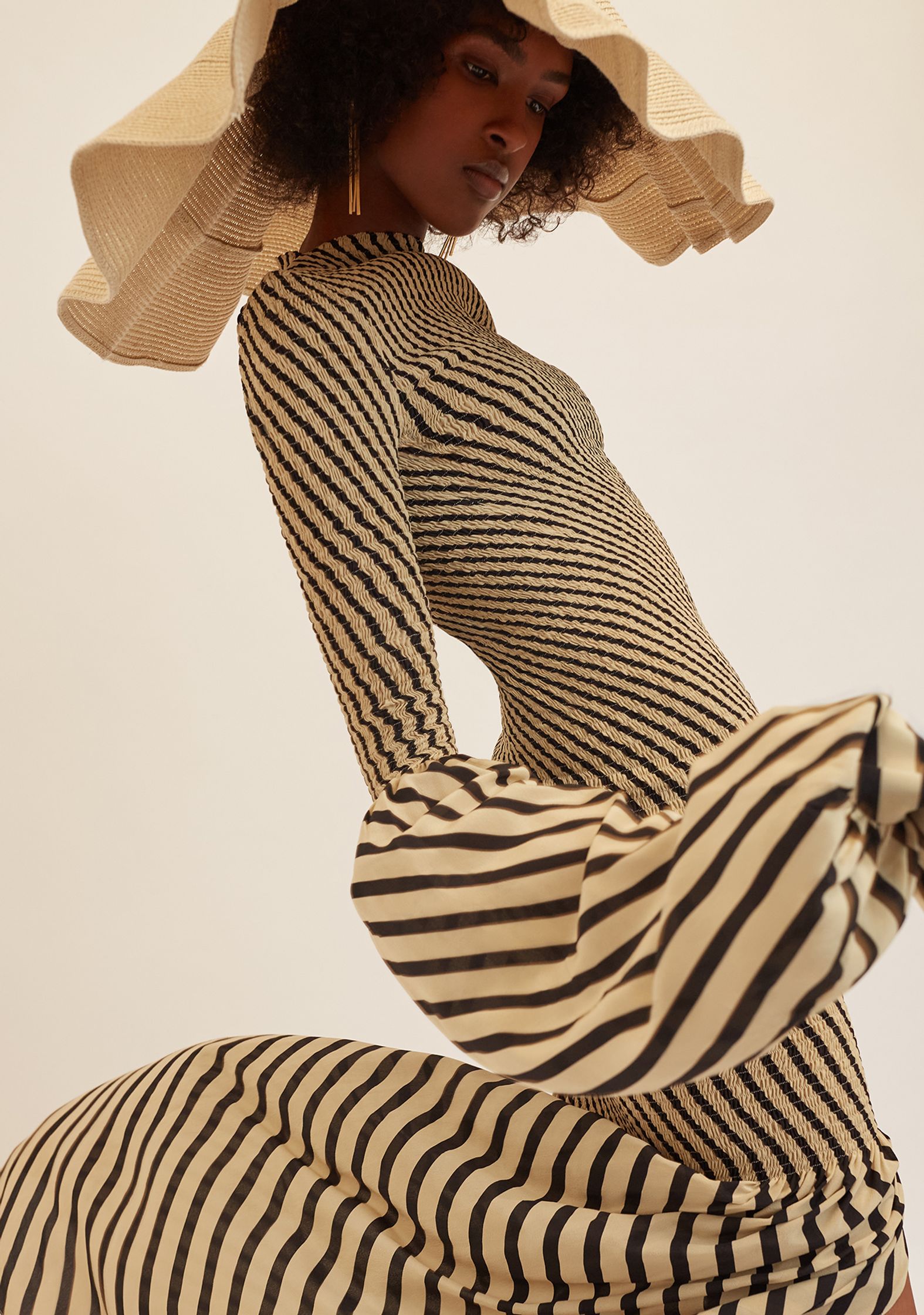 a black woman wearing a striped dress and a straw hat