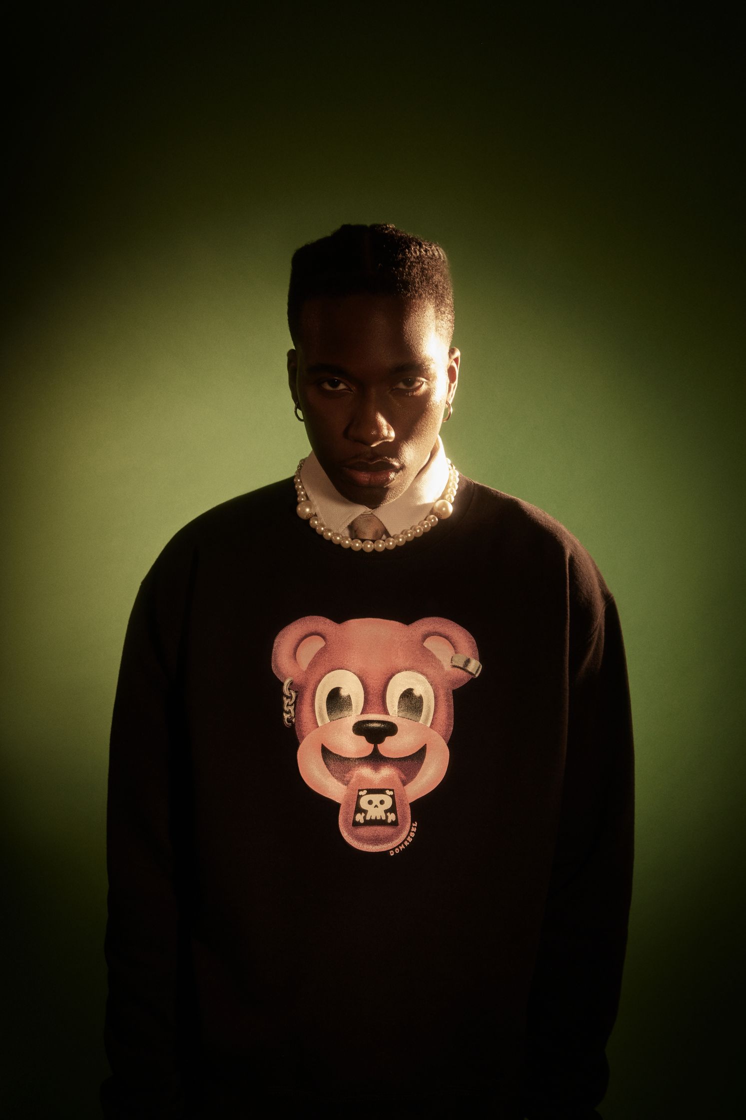 a man wearing a black sweater with a bear on it