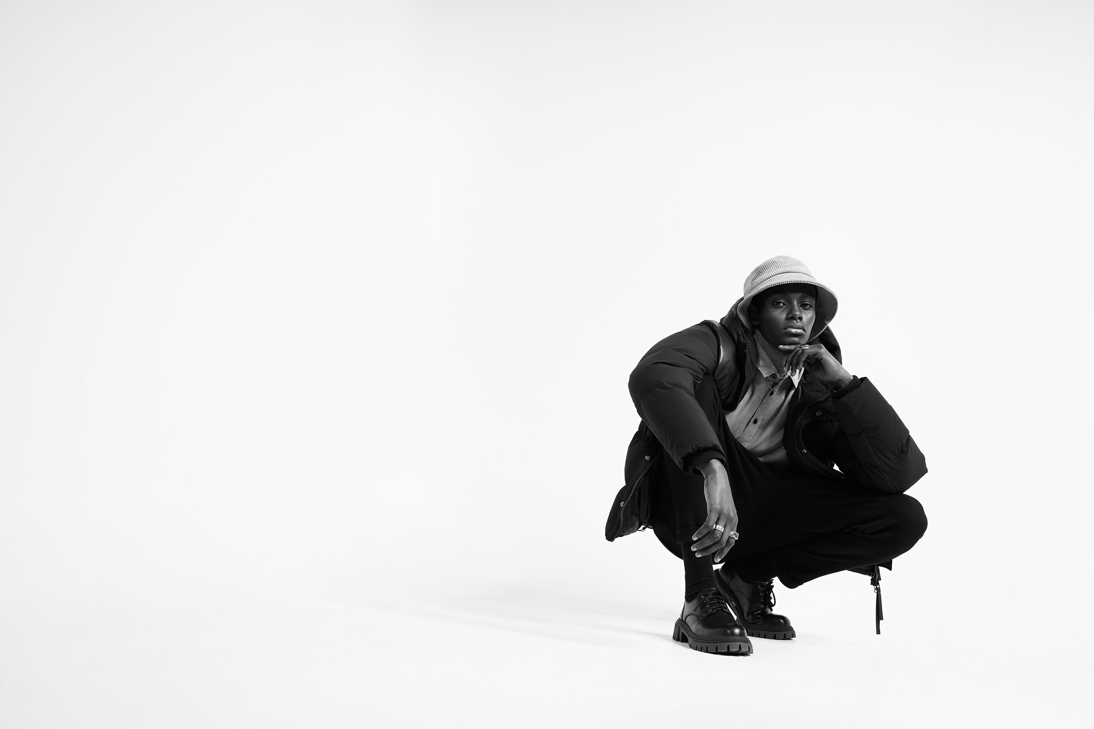a black and white photo of a man crouching on the floor