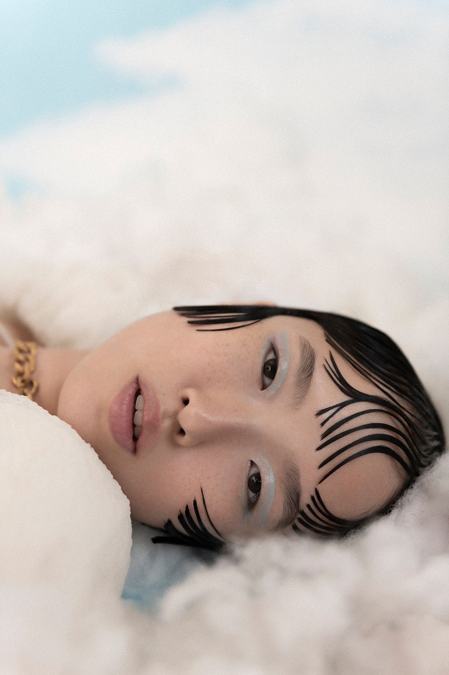 a woman laying on a cloud with makeup on her face