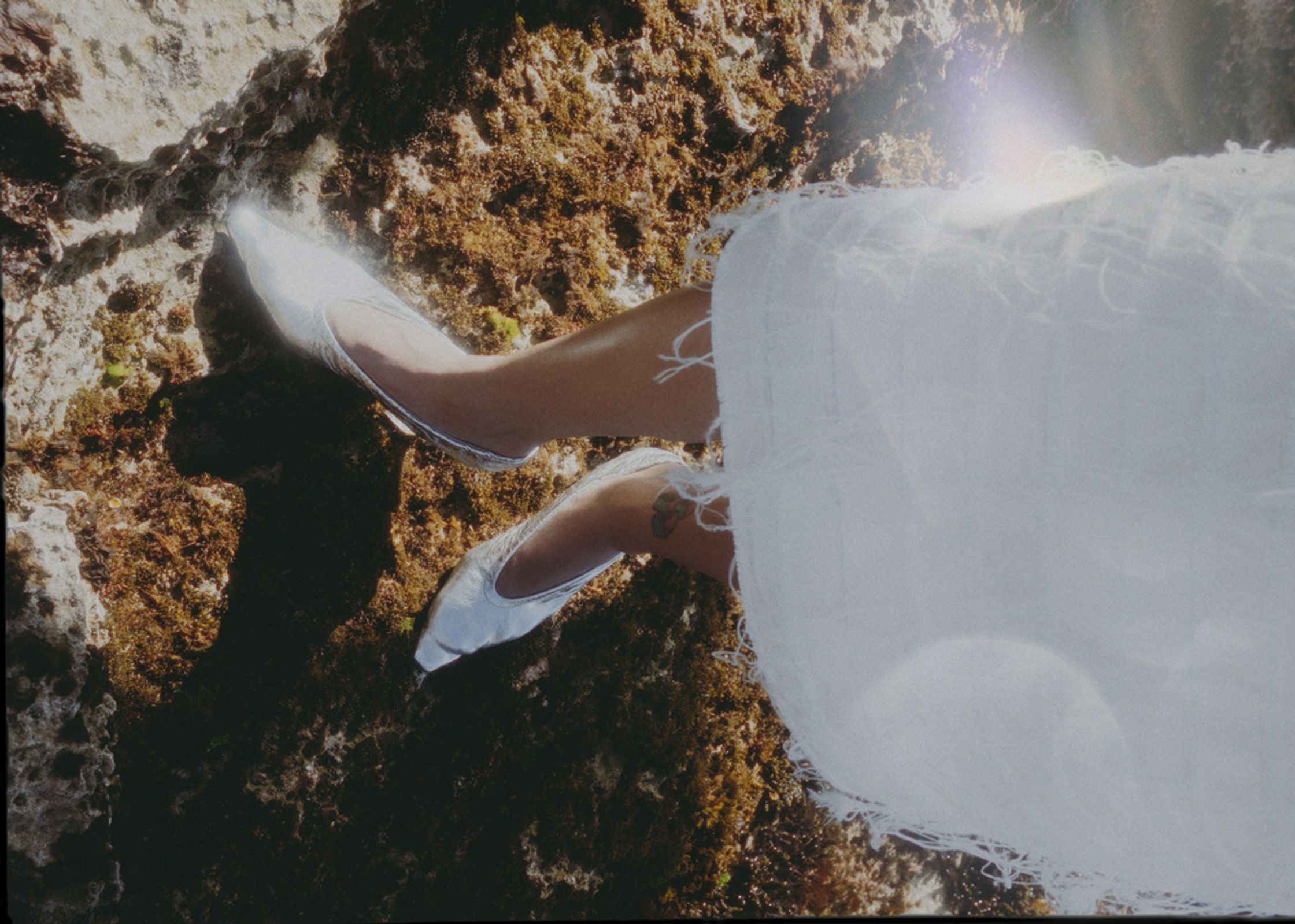 a woman in a white dress standing on a rock