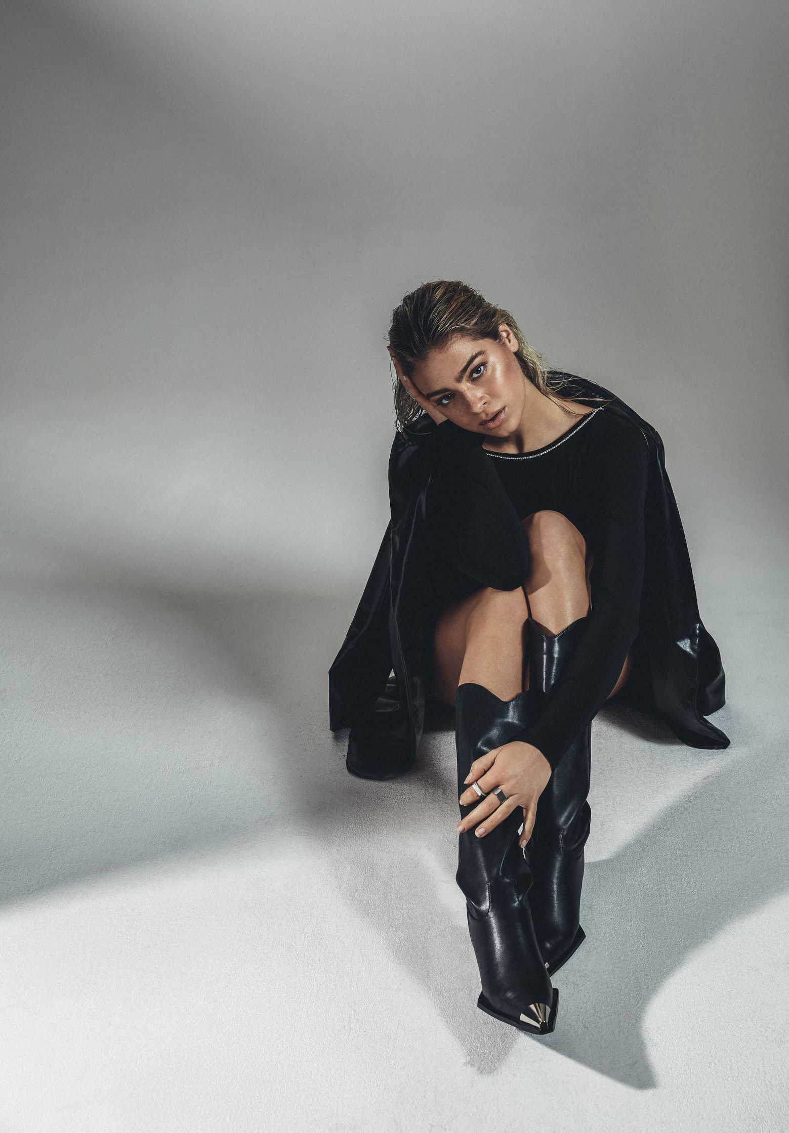 a woman sitting on the floor in black boots