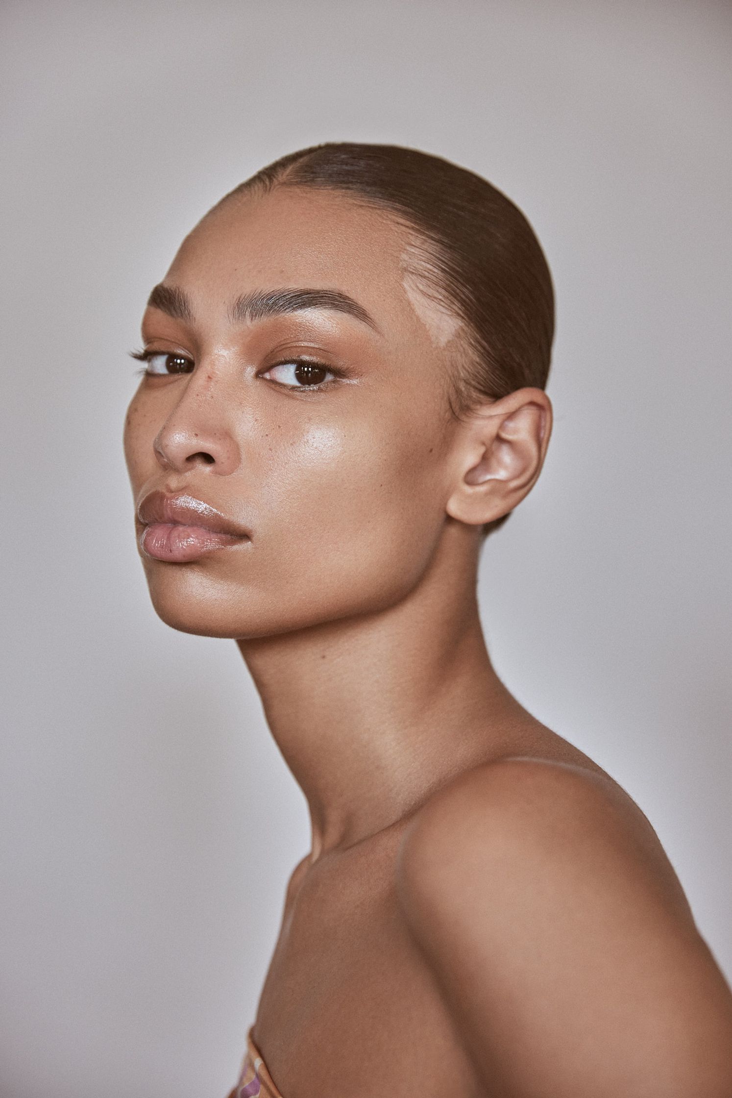 a young woman with a shaved head posing in front of a white background