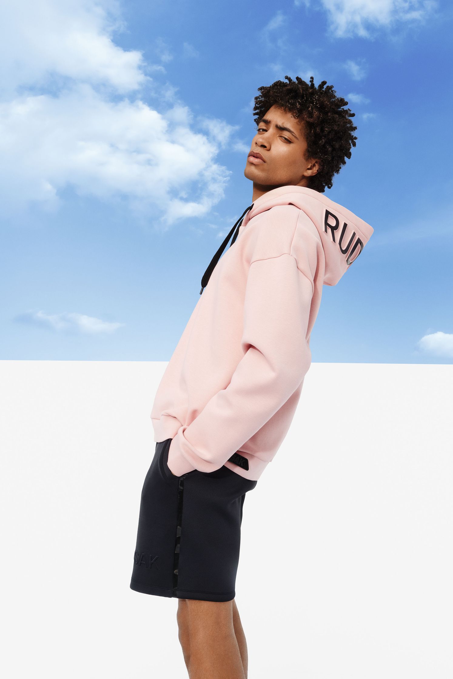 a young man wearing a pink hoodie and shorts
