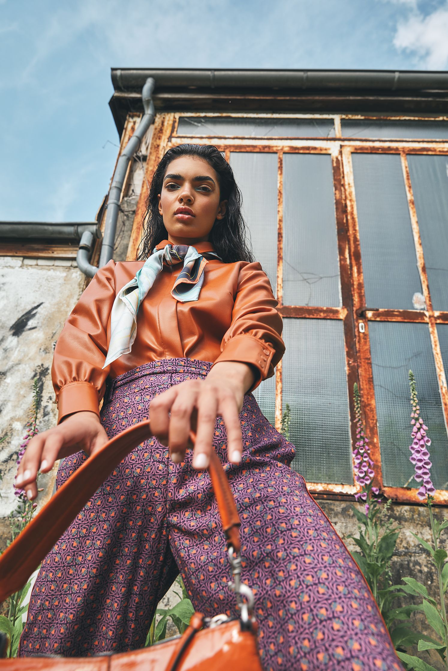a woman holding a purse in front of a building