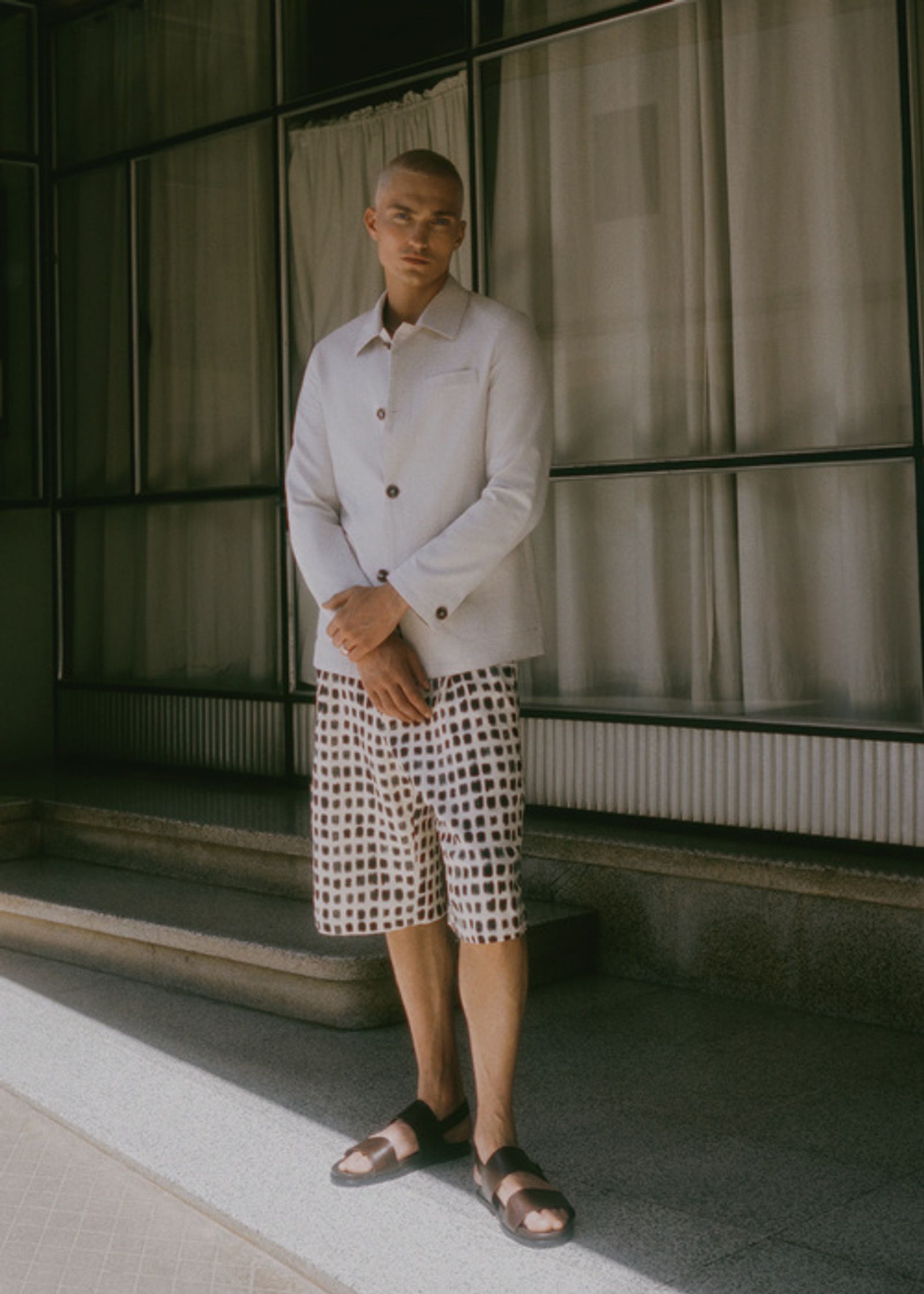 a man wearing a white blazer and patterned shorts
