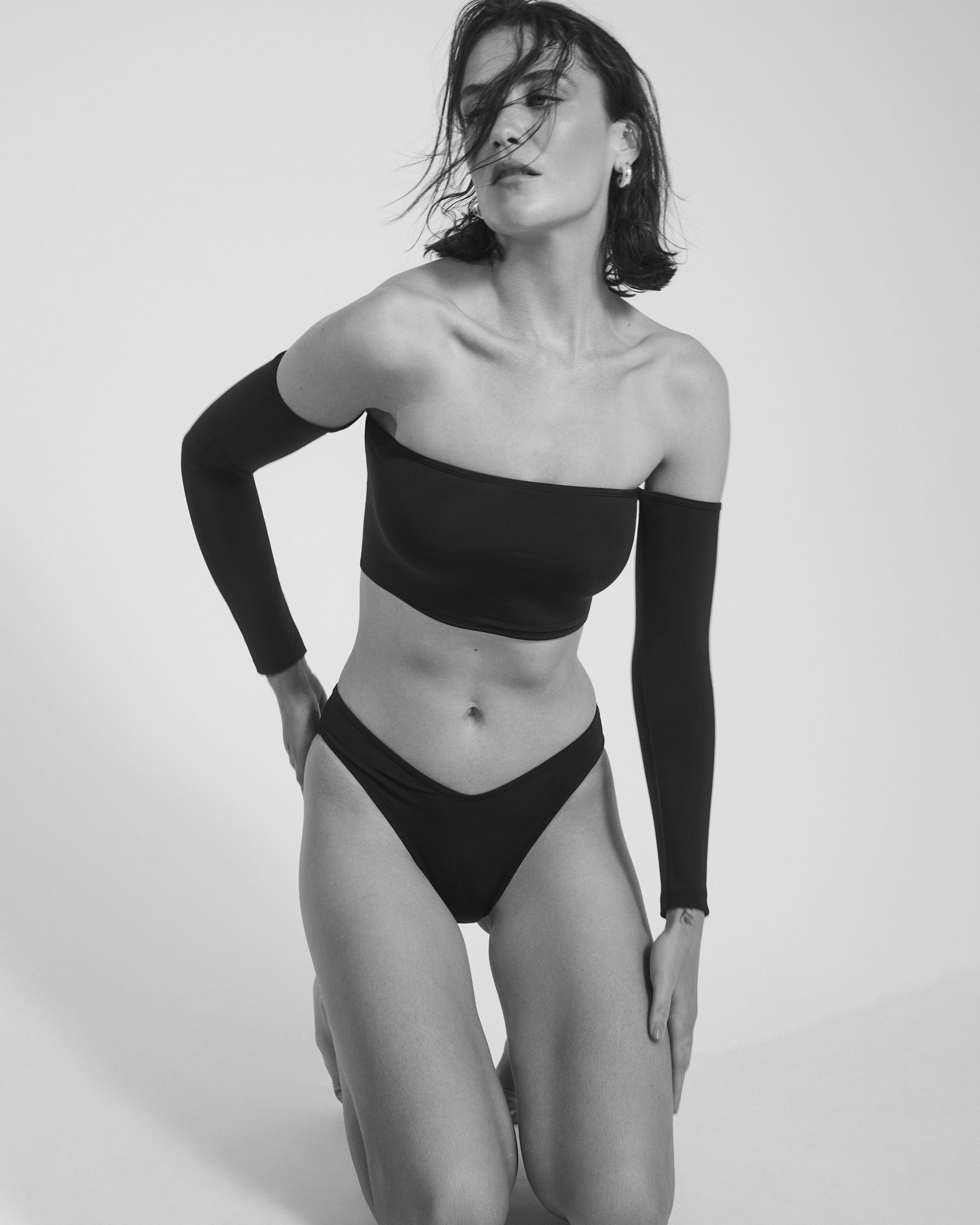 a woman in a black bikini posing on the floor