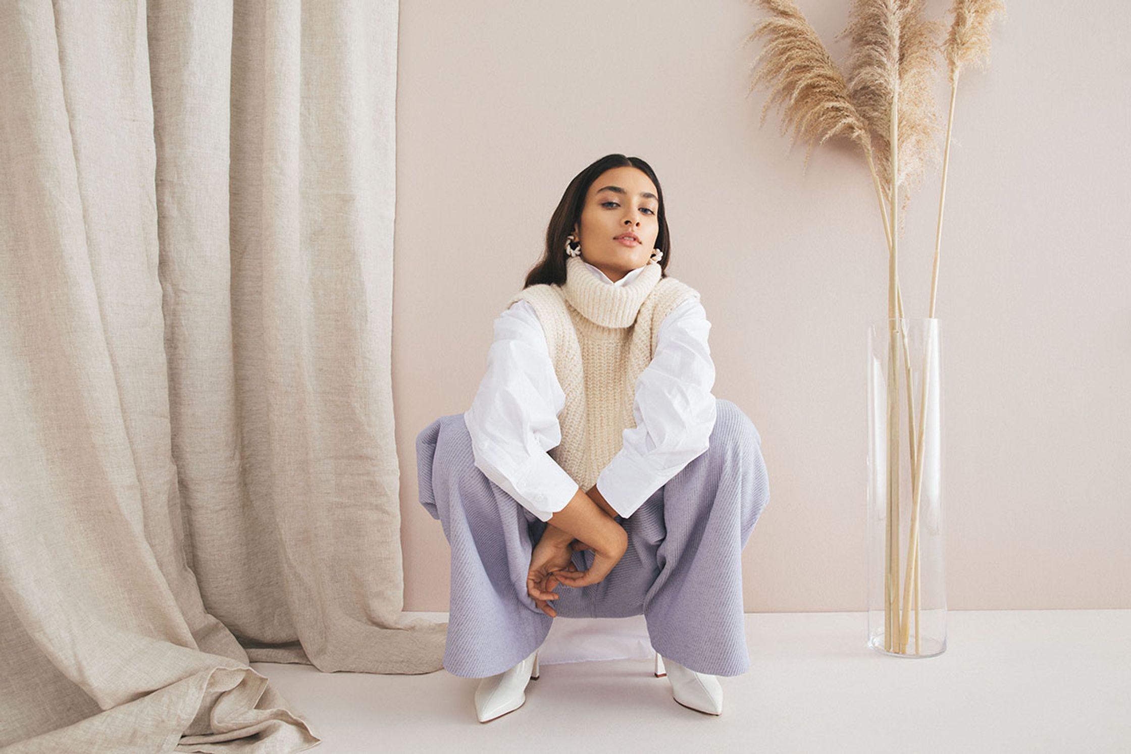 a woman wearing a white sweater and purple wide leg pants