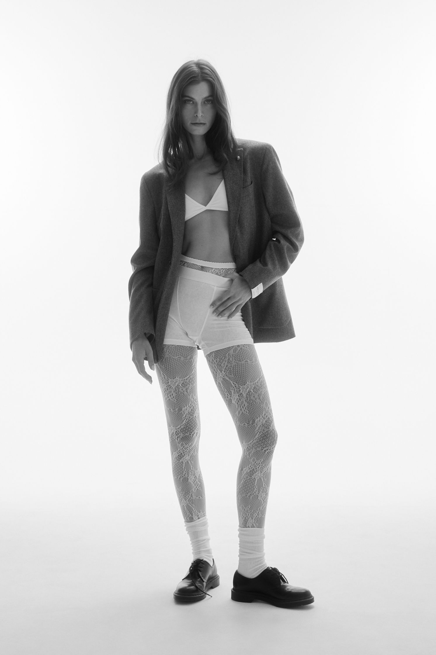 a black and white photo of a woman in tights and a blazer