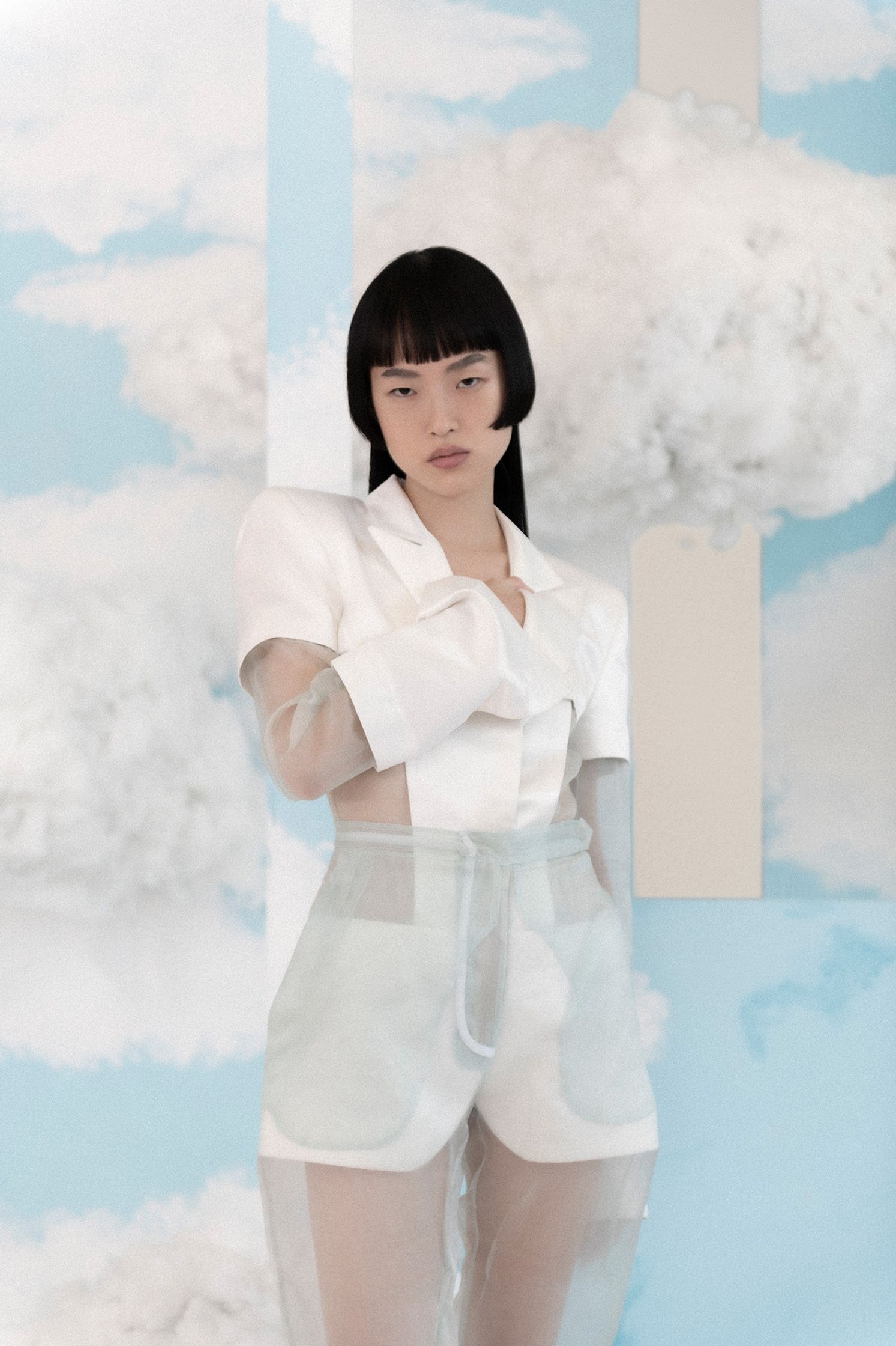 a woman in a white outfit posing in front of clouds
