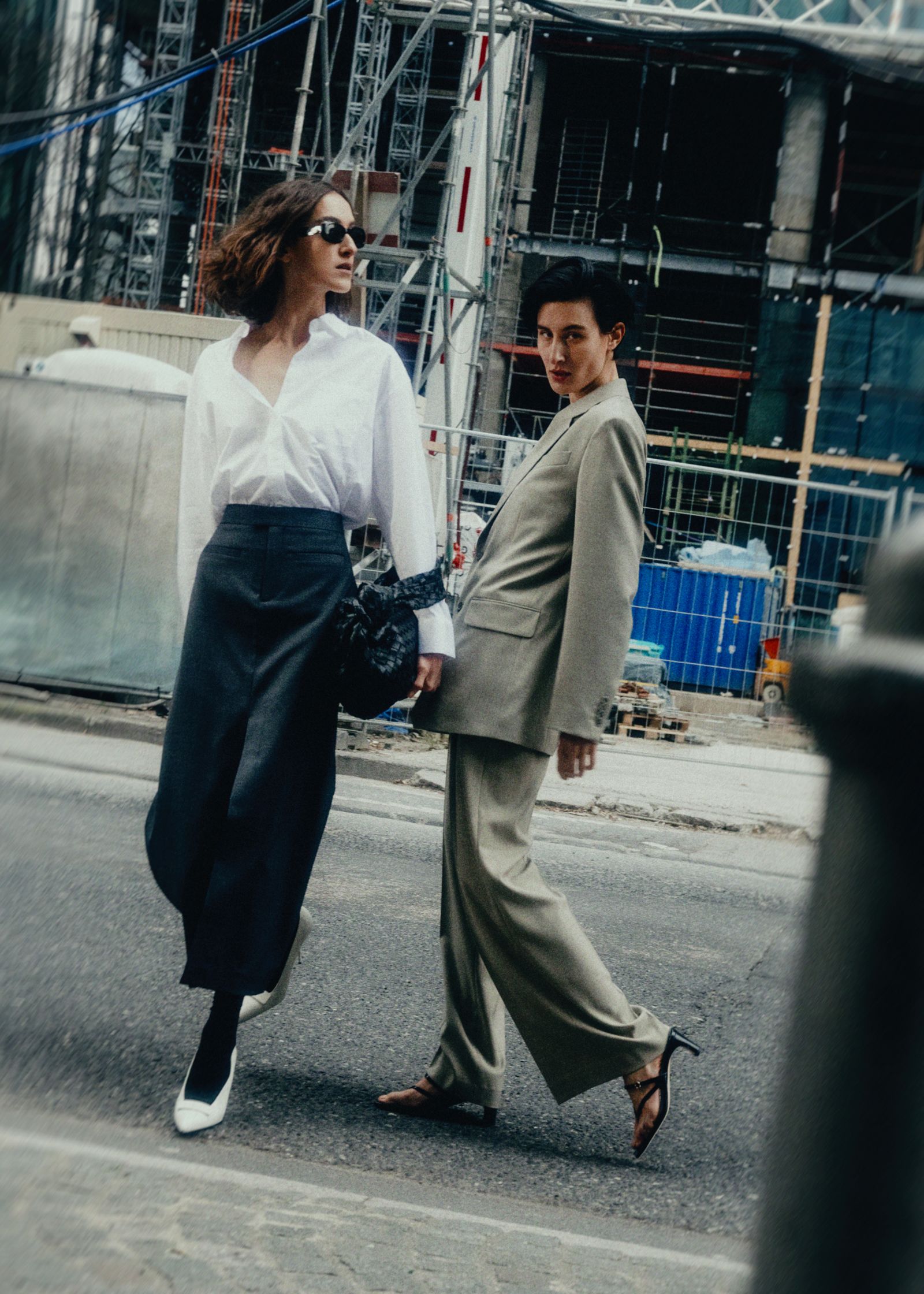 two women walking down the street in a suit and skirt