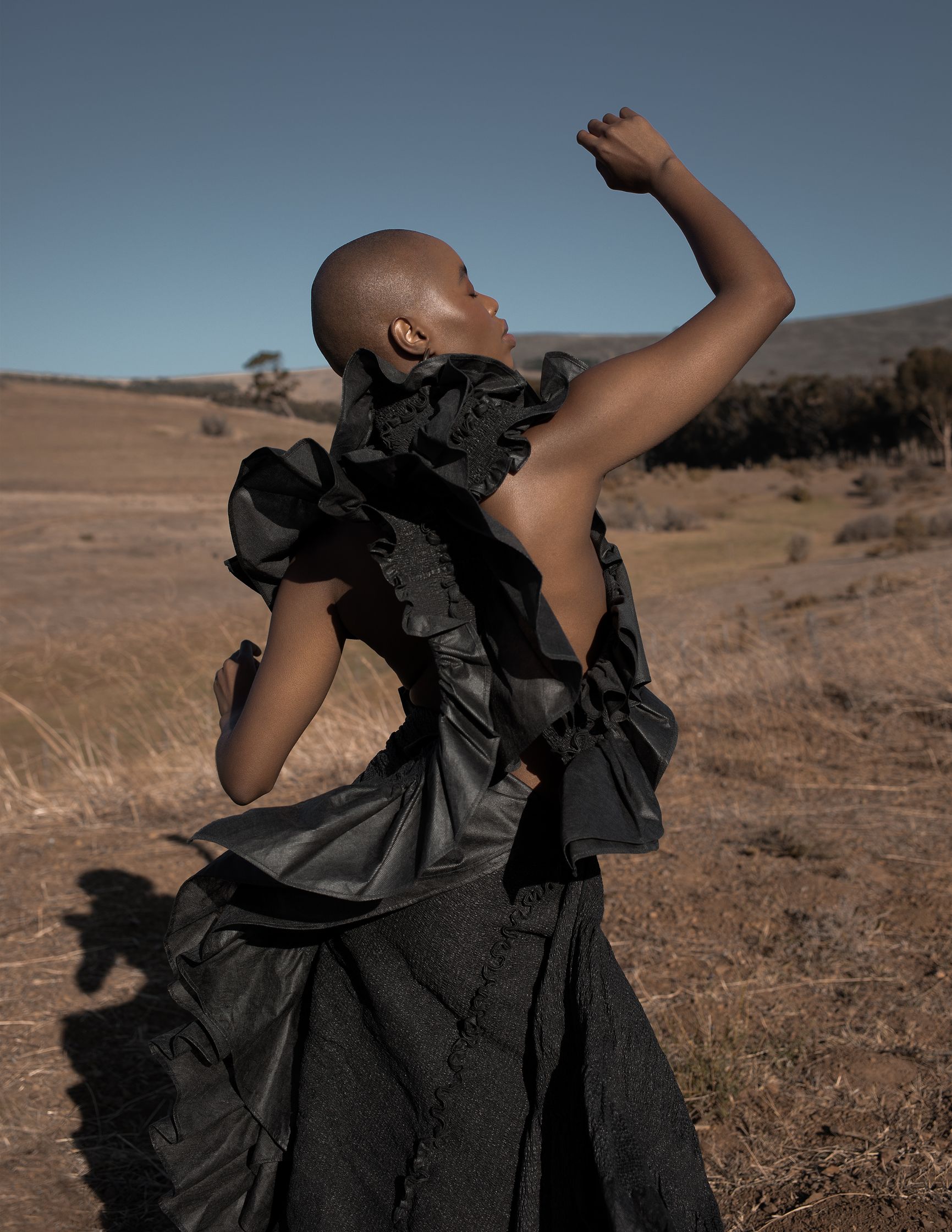 a woman in a black dress standing in a field