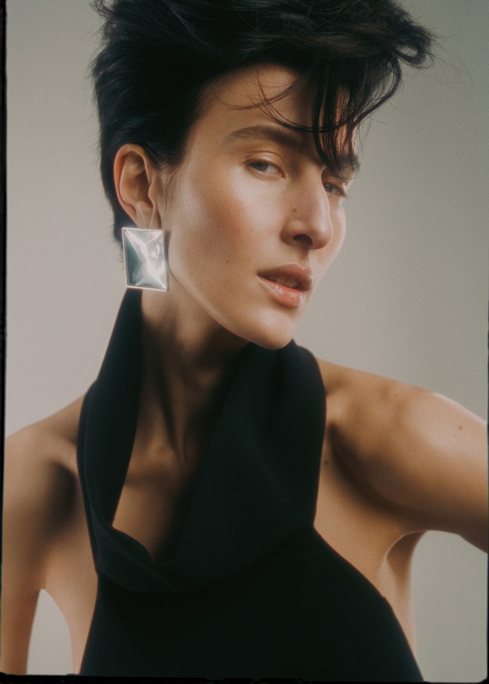 a woman wearing a black top and silver earrings