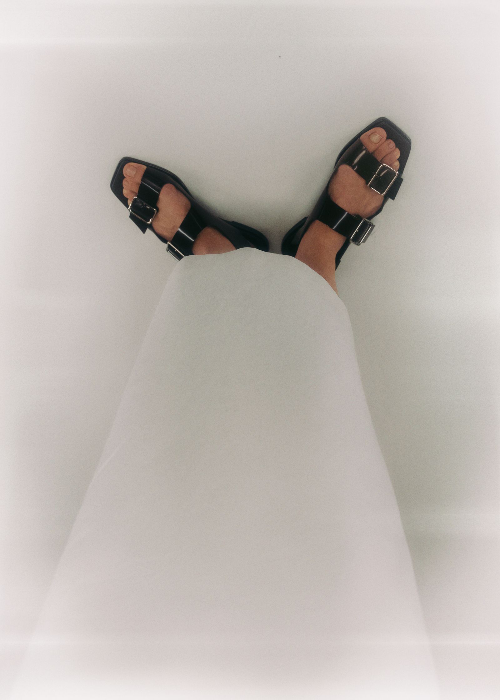 a person's feet in black sandals on a white background