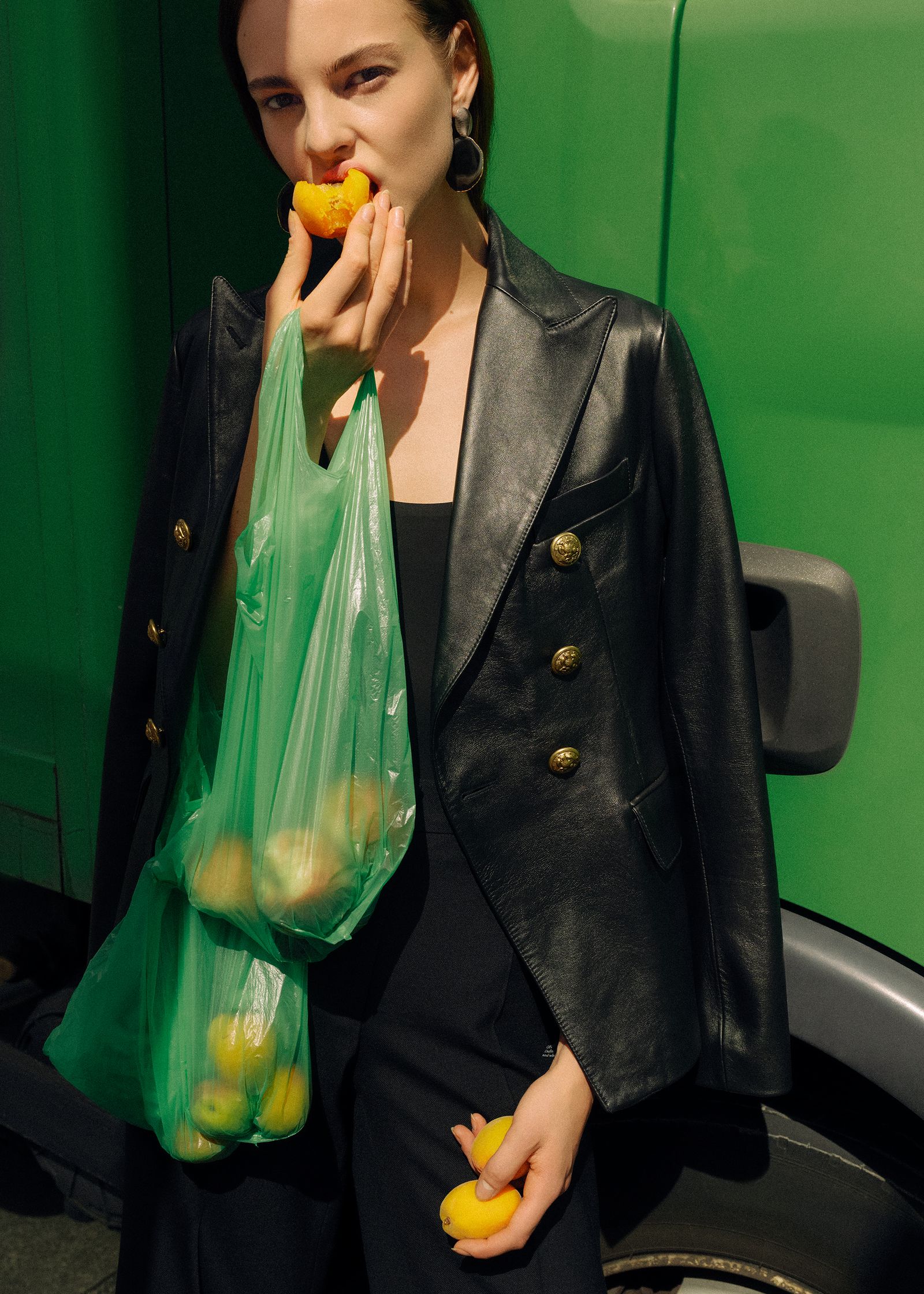a woman is holding a bag of oranges in front of a green truck