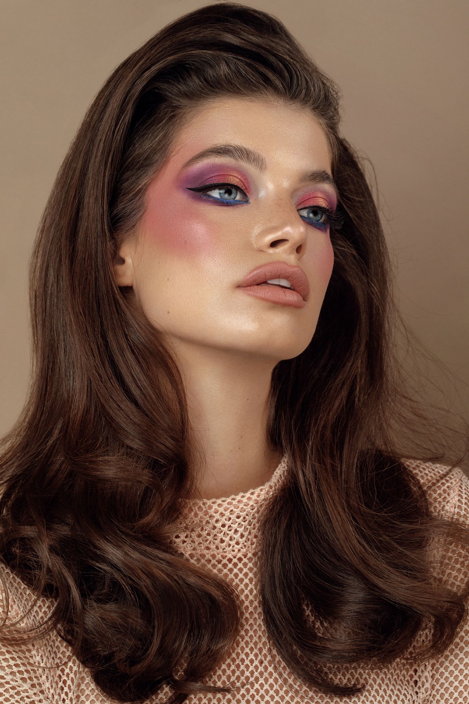 a woman with long brown hair and pink eye makeup