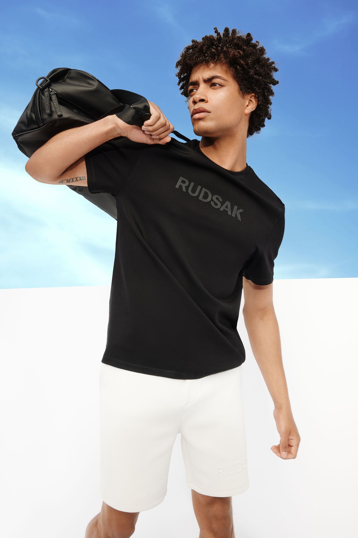 a man in a black t - shirt and shorts holding a bag