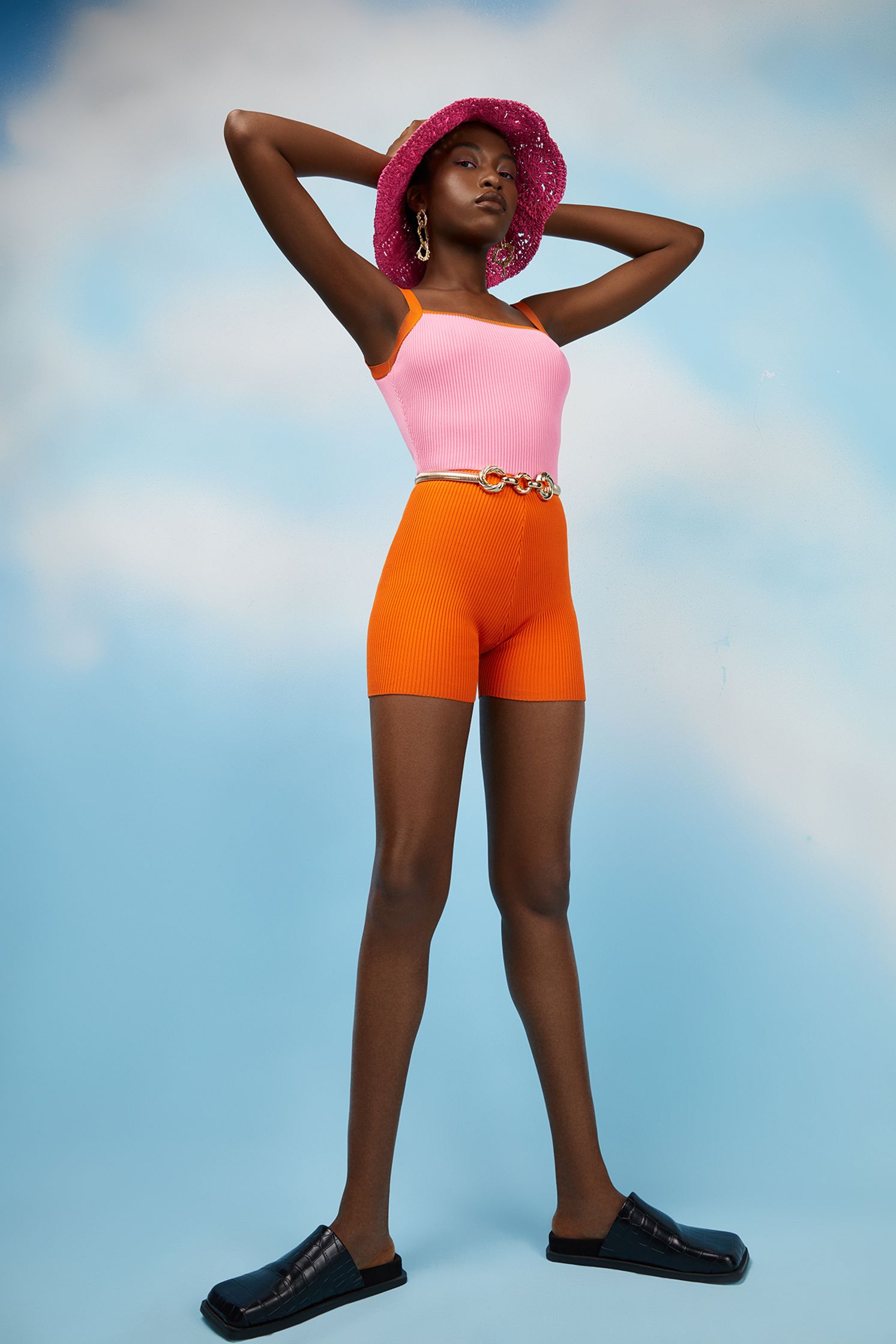 a black woman in orange shorts and a pink hat