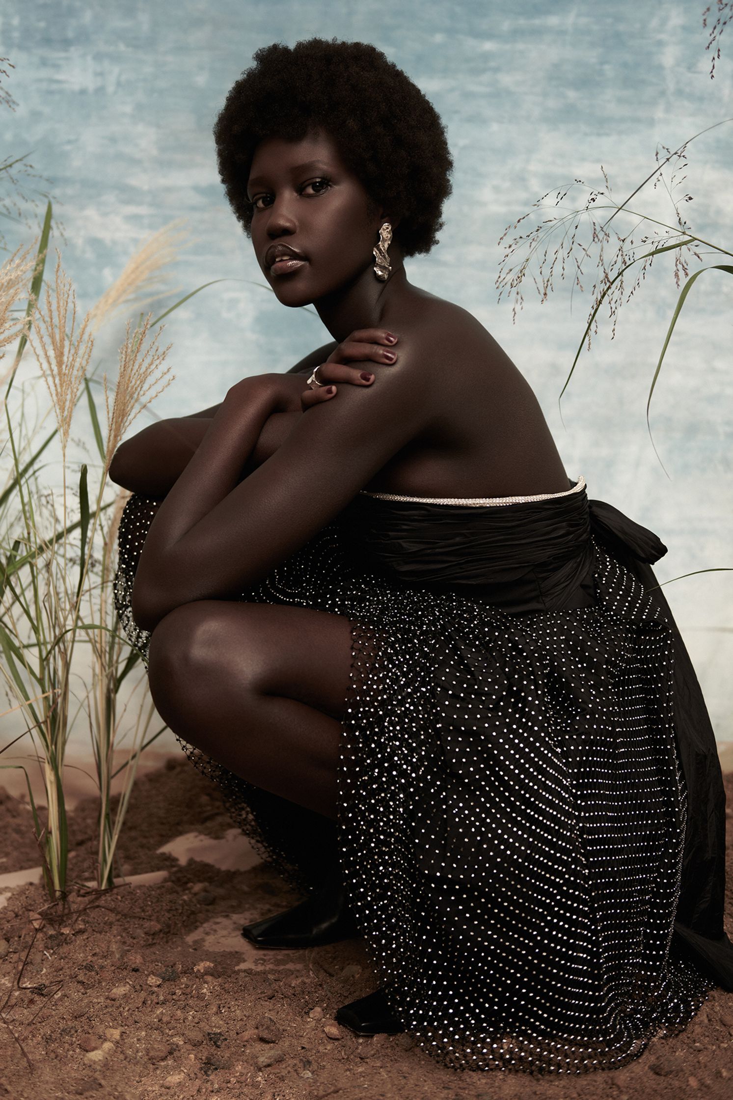 a woman in a black dress crouching in the grass