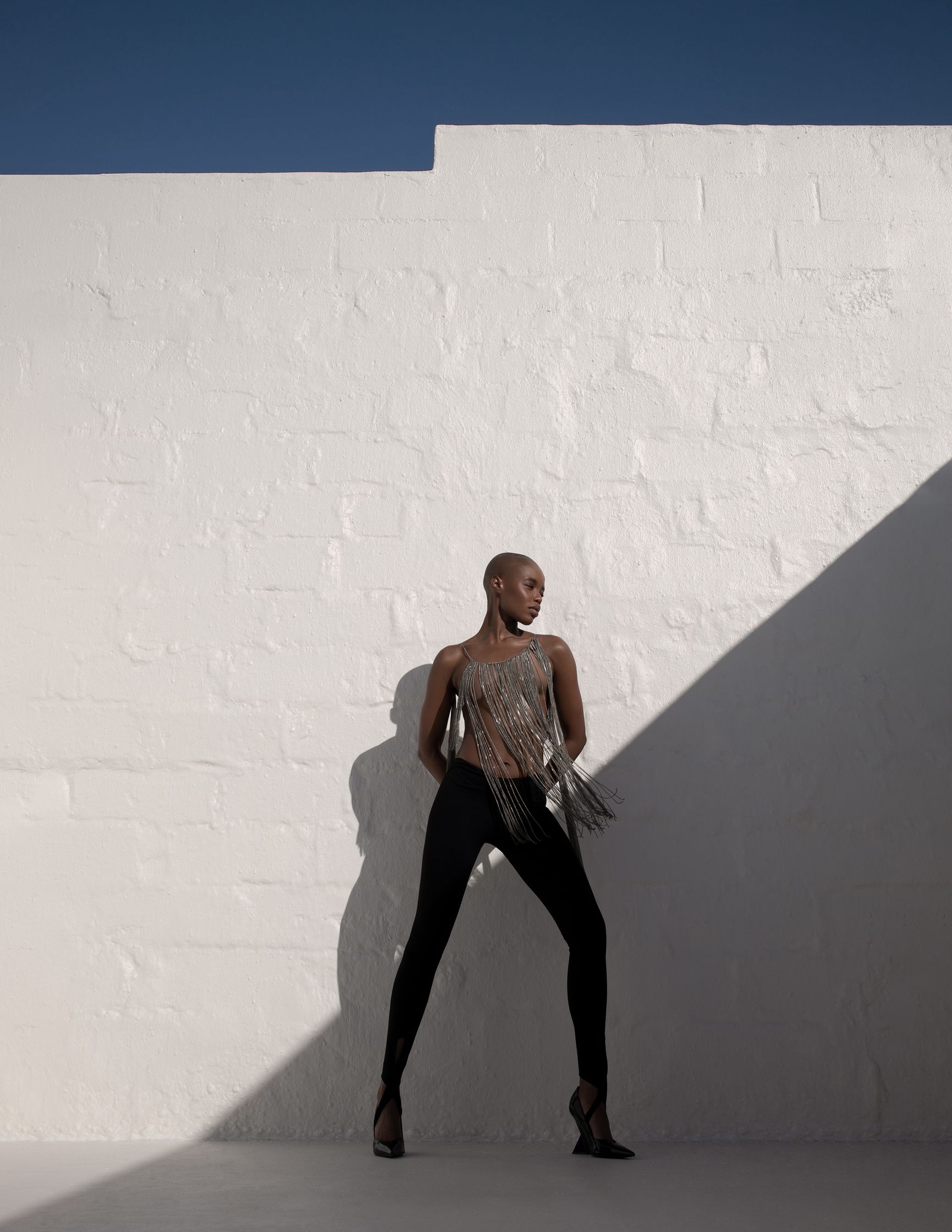 a woman leaning against a white wall