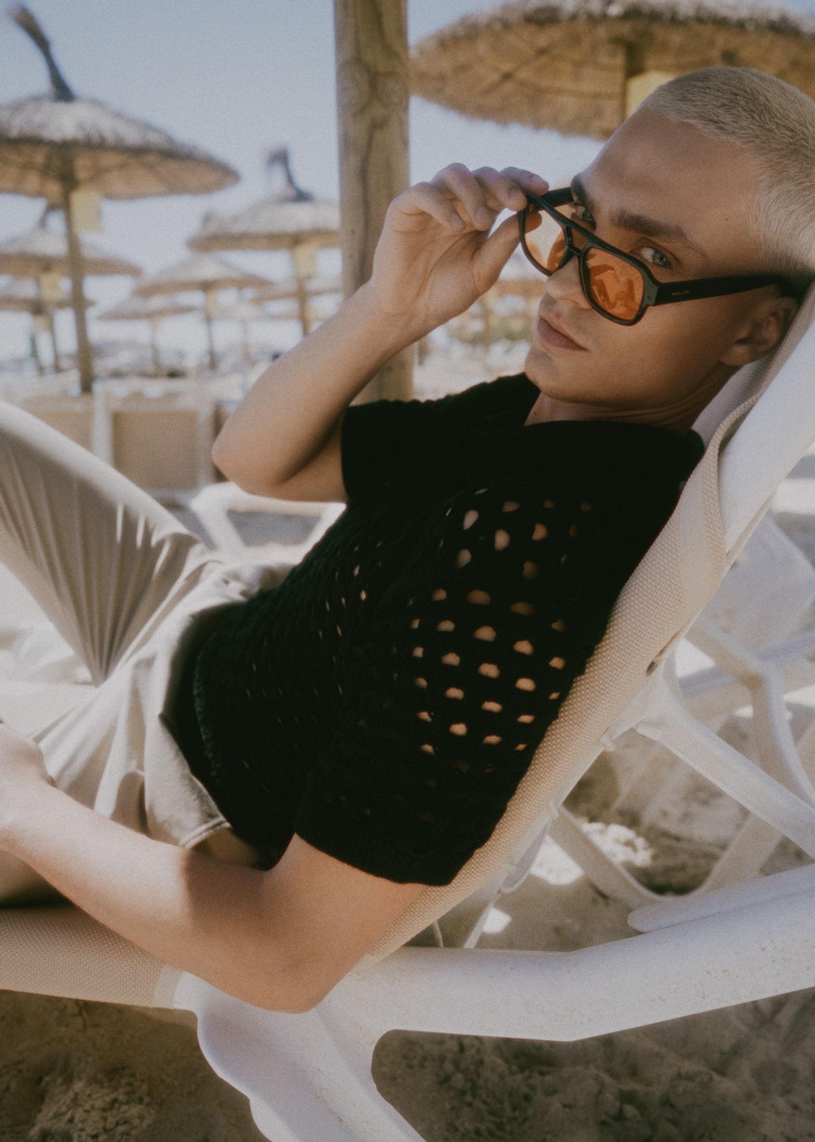 a man laying on a beach chair wearing sunglasses