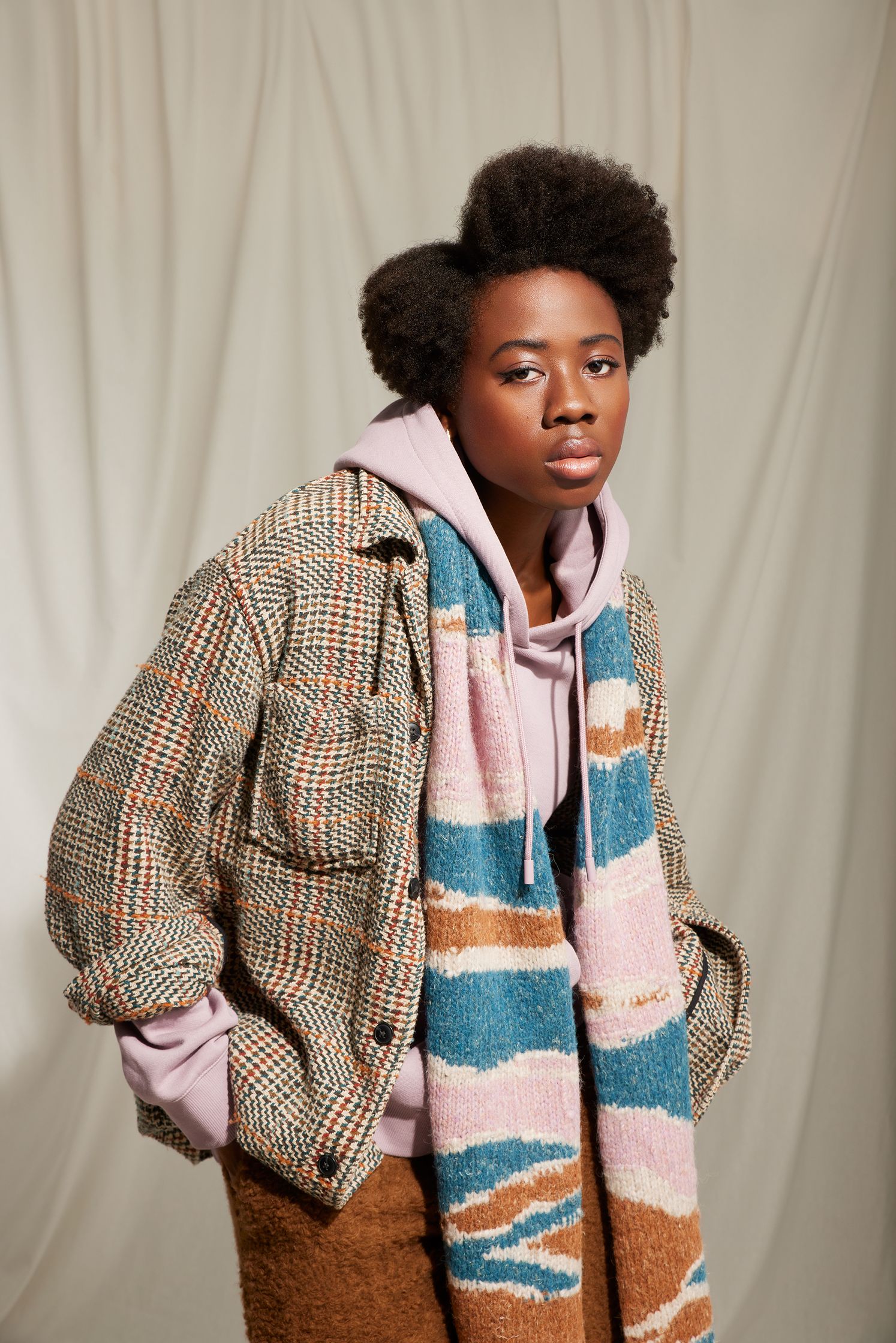 a black woman wearing a plaid jacket and scarf