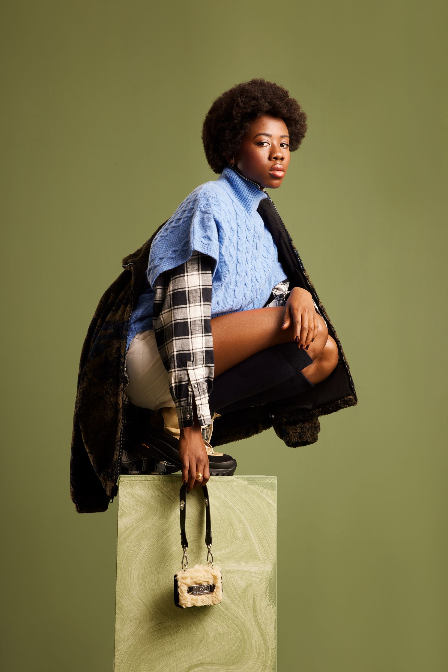 a black woman sitting on top of a block holding a bag
